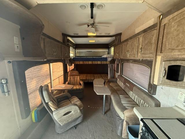 RV rental interior: living area with recliners, long sofa, overhead bunk beds, and compact kitchen for comfort on the road.. Weekend Warrior 3505 Le 2008