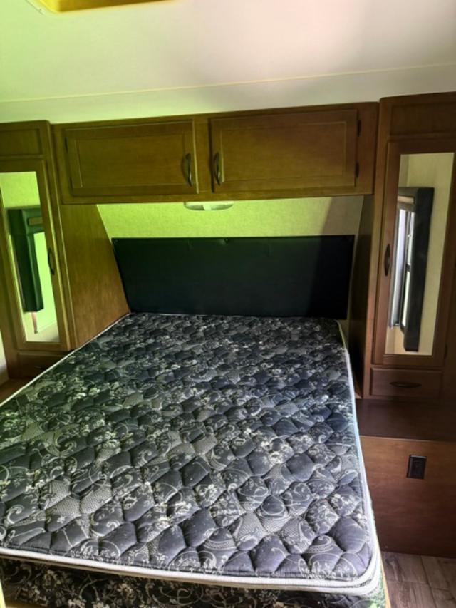RV rental bedroom: a bed with patterned mattress, black headboard, and wood cabinets with mirrored doors.. Pacific Coachworks Powerlite 2016