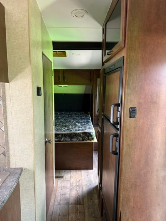 RV rental: A compact interior showing a hallway leading to a bedroom, with a fridge and kitchen on the right. Green lighting.. Pacific Coachworks Powerlite 2016