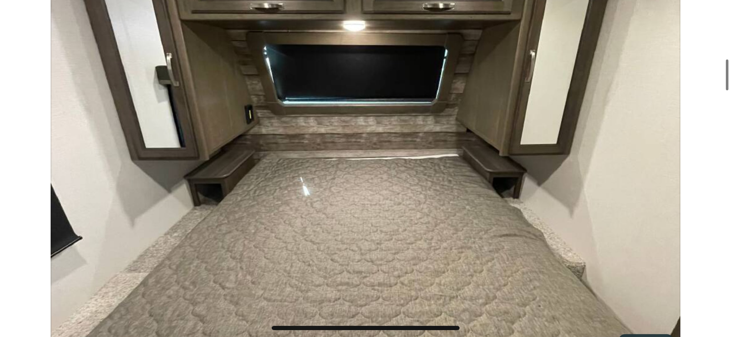 RV rental bedroom with a cozy bed, overhead cabinets, and a window for comfortable travel.. Keystone RV Cougar 2022