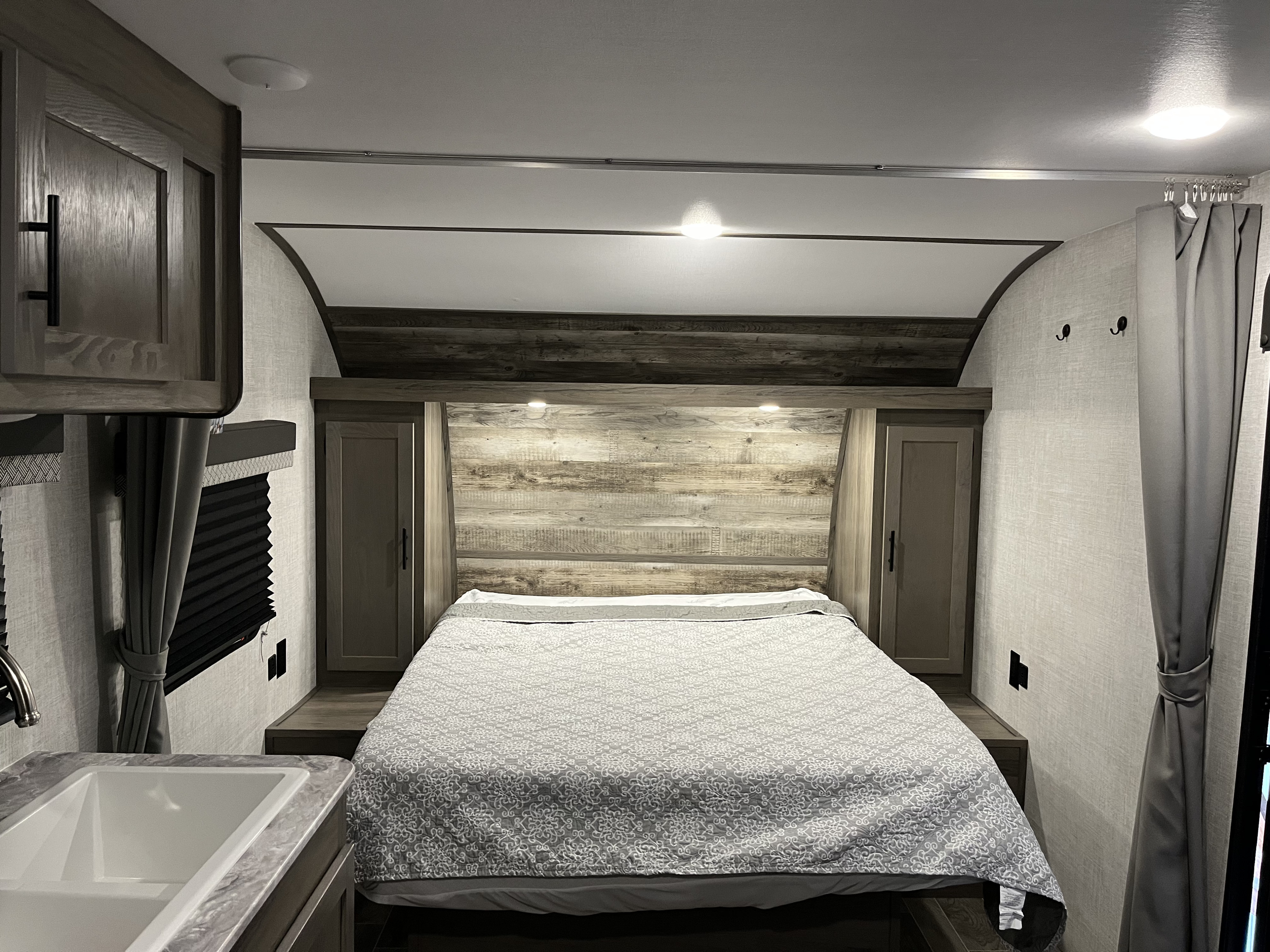 Cozy RV rental bedroom with a comfy bed, wood-look headboard, and compact amenities. Ideal for a camper vacation.. Gulf Stream Conquest 2022