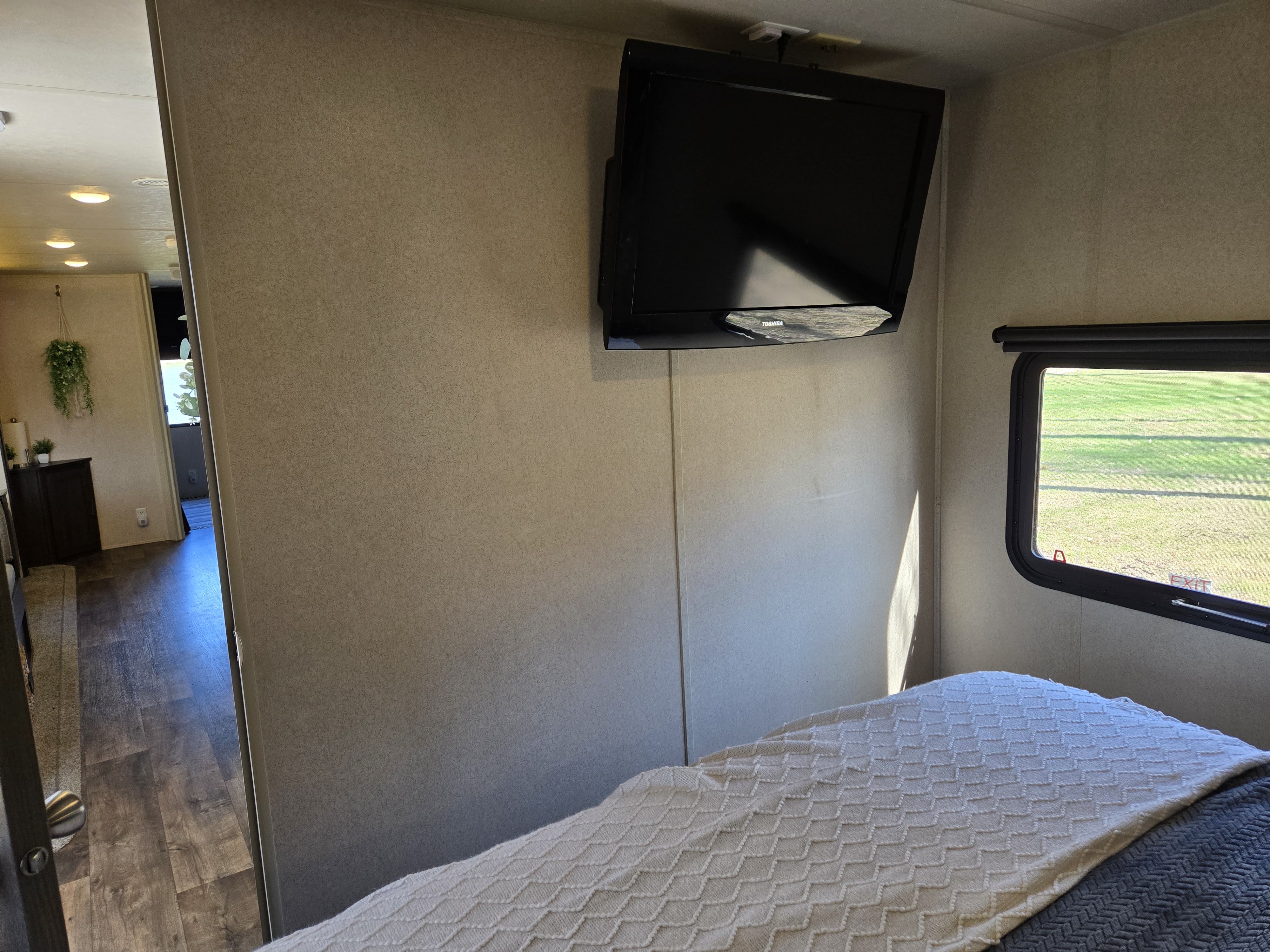 Bedroom in an RV rental featuring a comfortable bed, wall-mounted TV, and bright window with a view.. Forest River Salem 2018