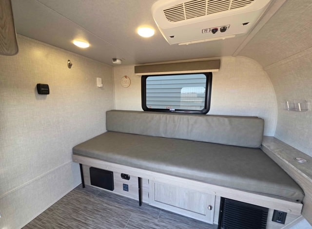 Cozy RV rental interior featuring a bench/bed, window, AC unit, and built-in storage.. Forest River Rockwood Geo Pro 2021
