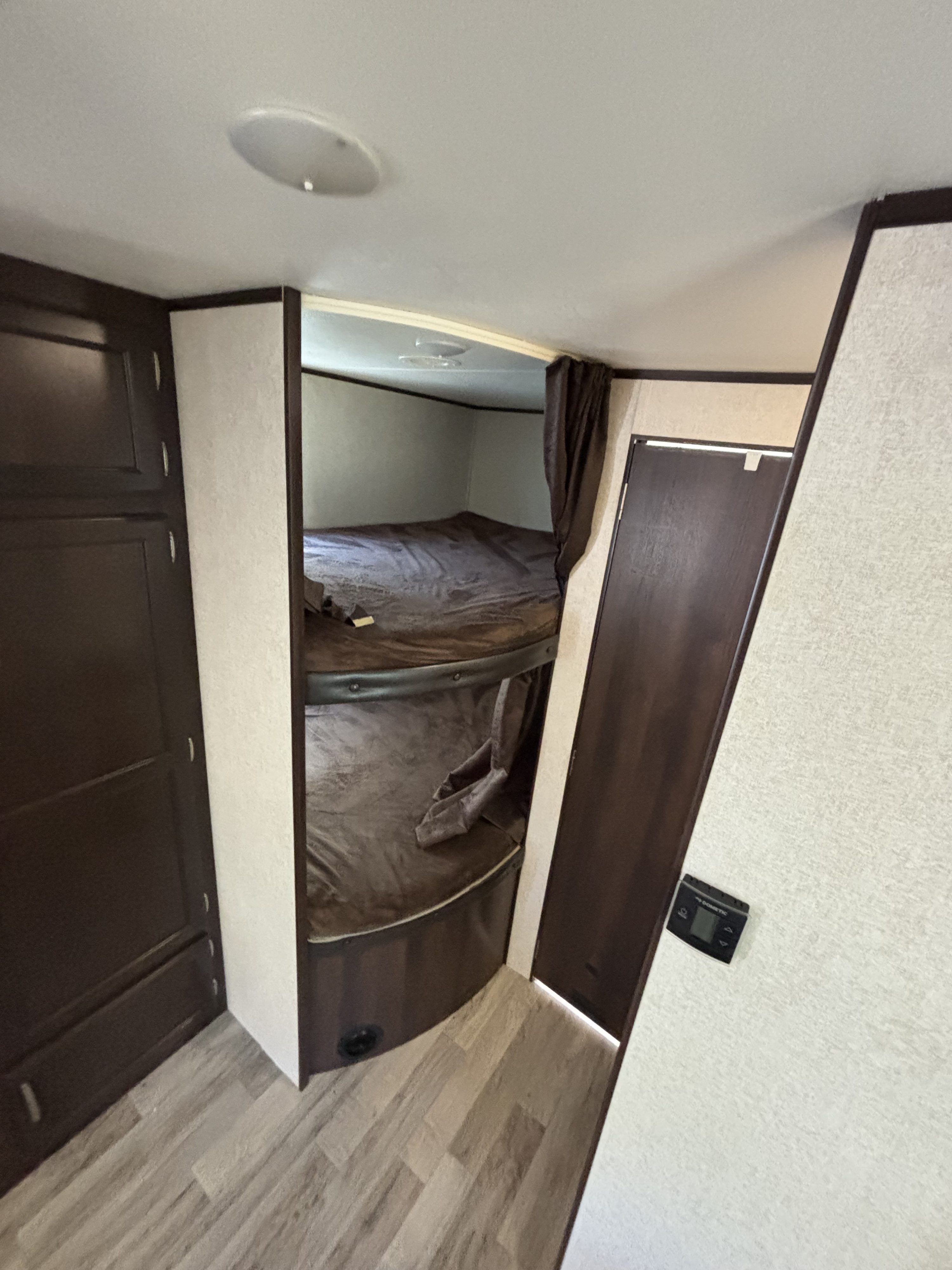 RV rental interior featuring comfortable bunk beds with storage cabinetry and a thermostat, perfect for families.. Jayco Jay Flight 2020