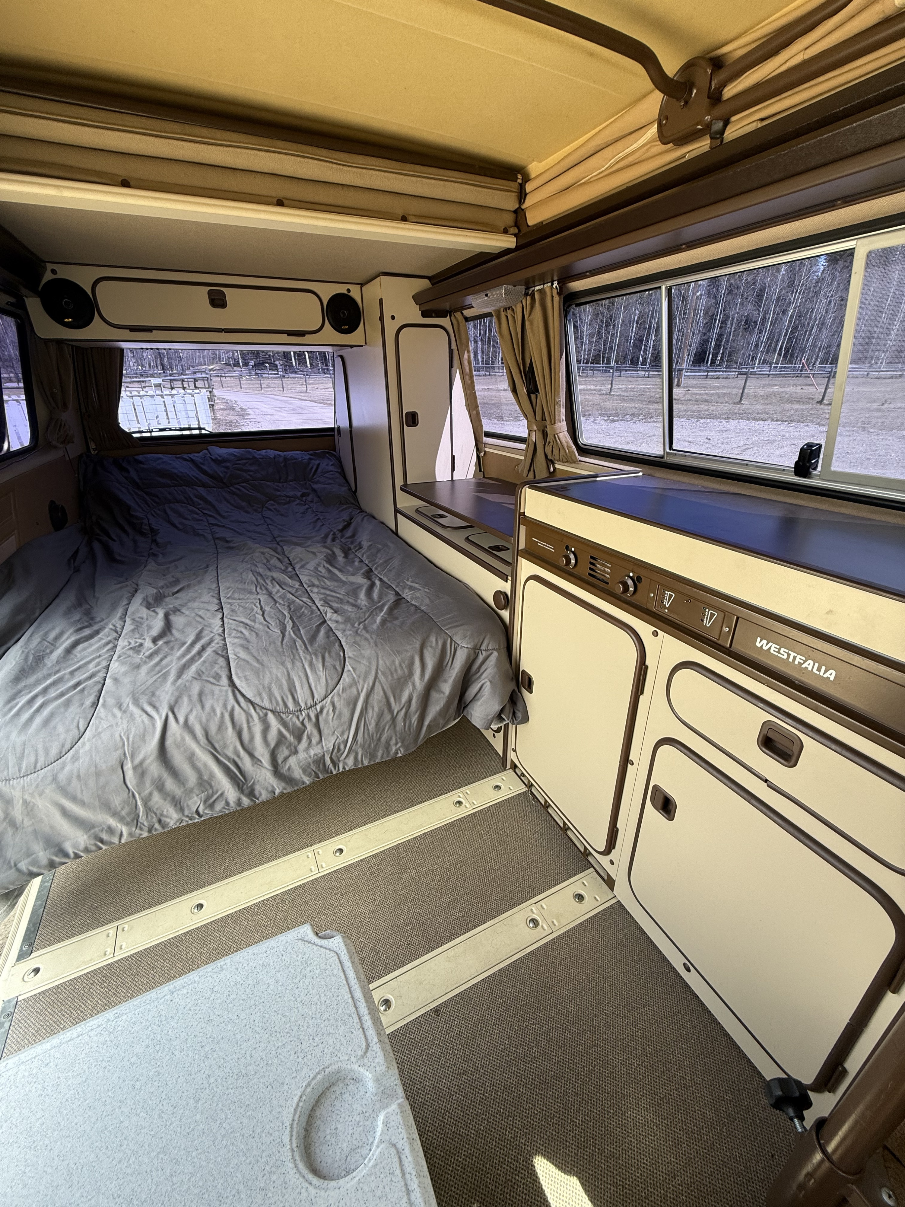 Step inside this classic Westfalia camper van. Ideal for an rv rental, it offers a bed, kitchen, and pop-top, with scenic outdoor views.. Volkswagen T3 1985