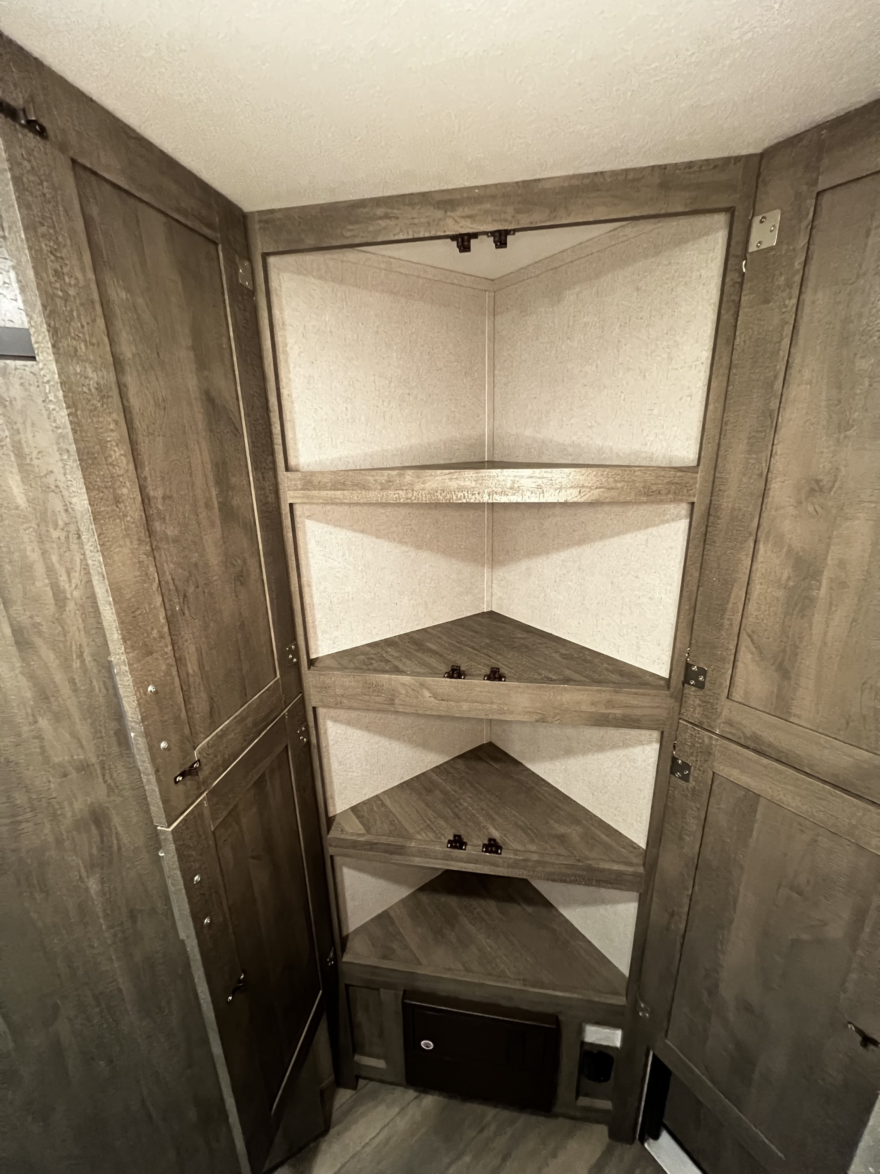 Discover this RV rental's clever corner storage unit with triangular shelves and an access panel for smart space organization.. Forest River XLR Micro Boost 29LRLE 2022