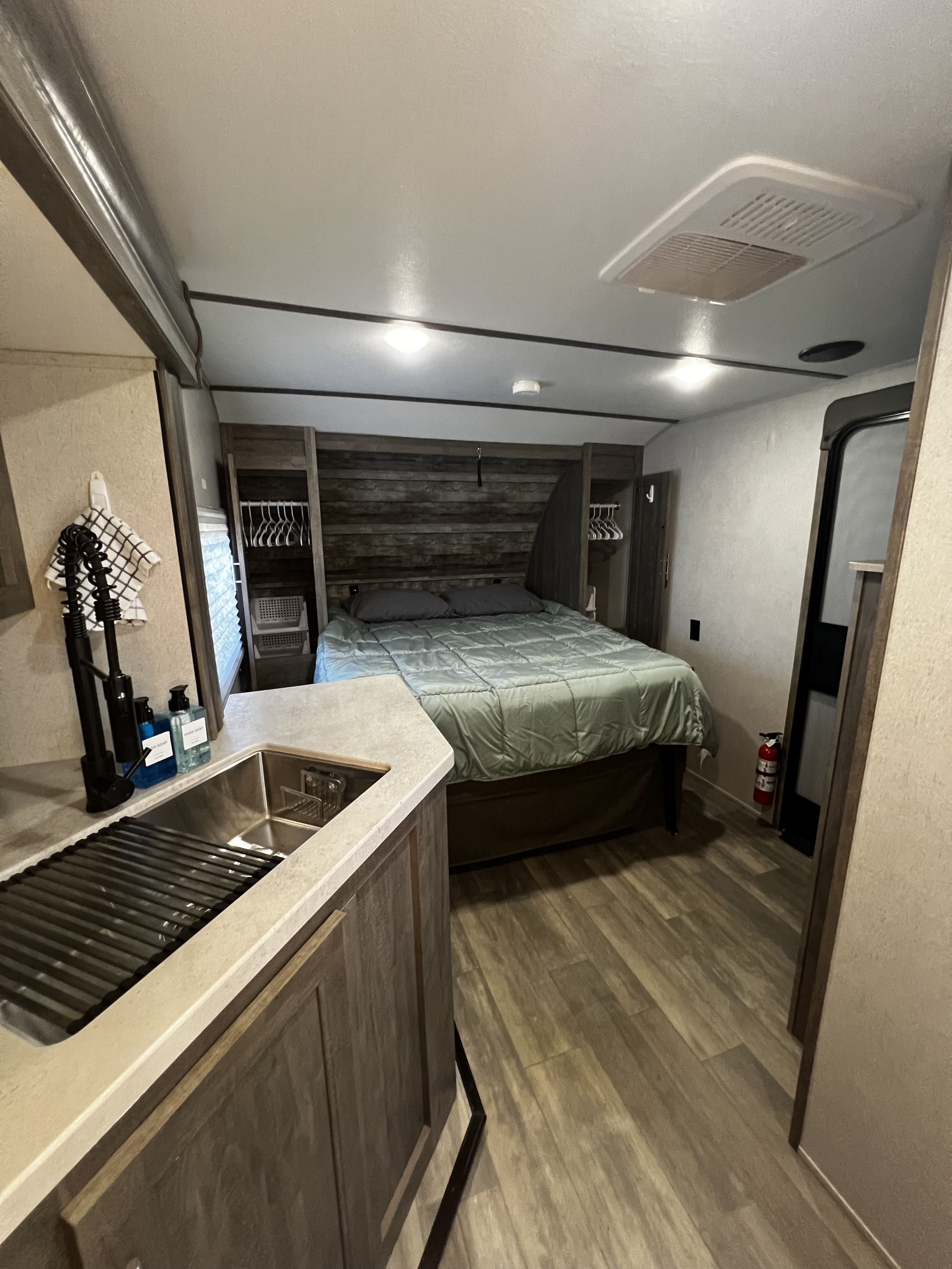 An rv rental interior featuring a modern bedroom with storage and a compact kitchen counter with sink.. Forest River XLR Micro Boost 29LRLE 2022