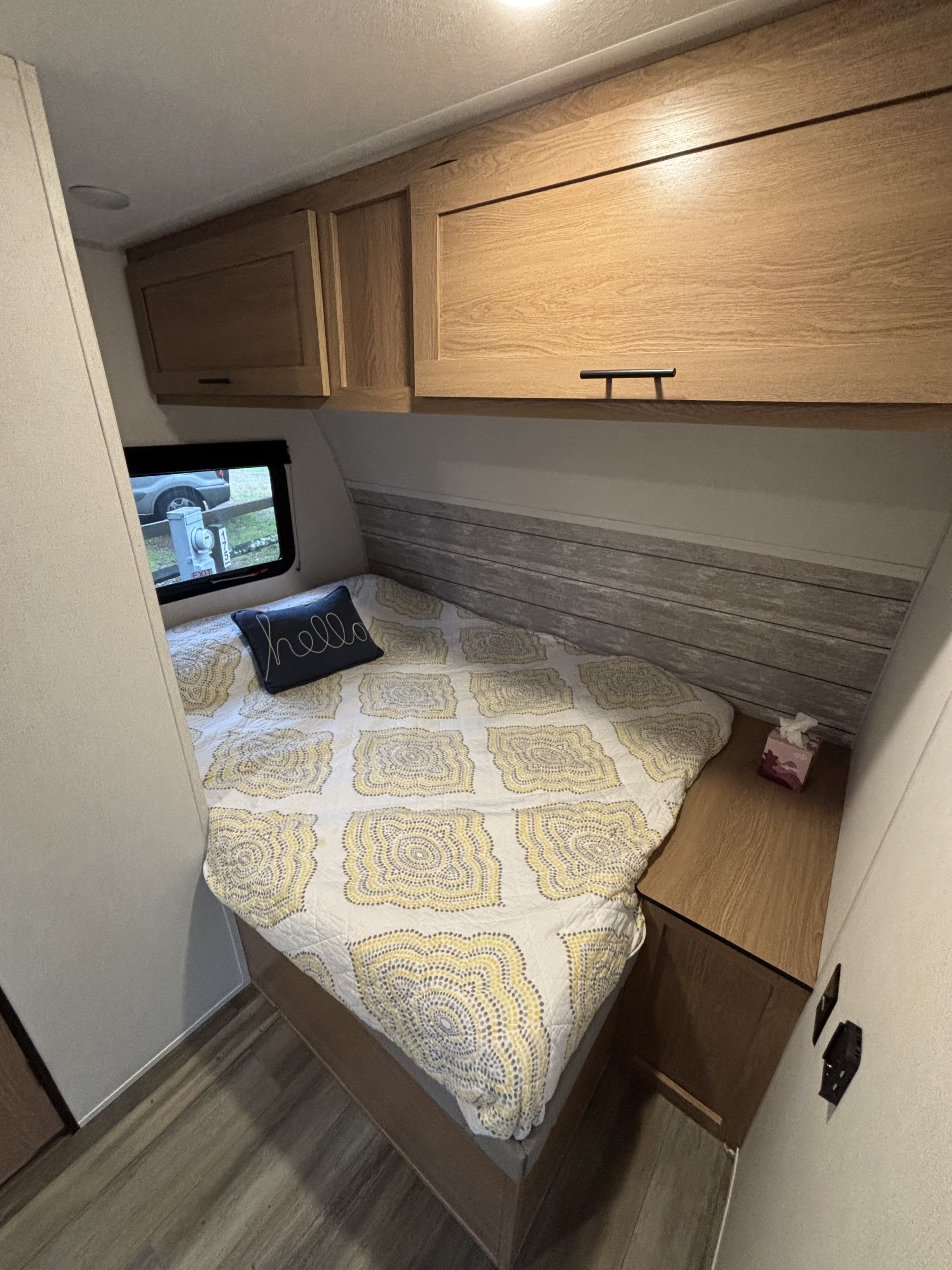 This RV rental bedroom offers a patterned bed, light wood cabinets, and a window, creating a cozy and compact living space.. Avenger 16RD 2024
