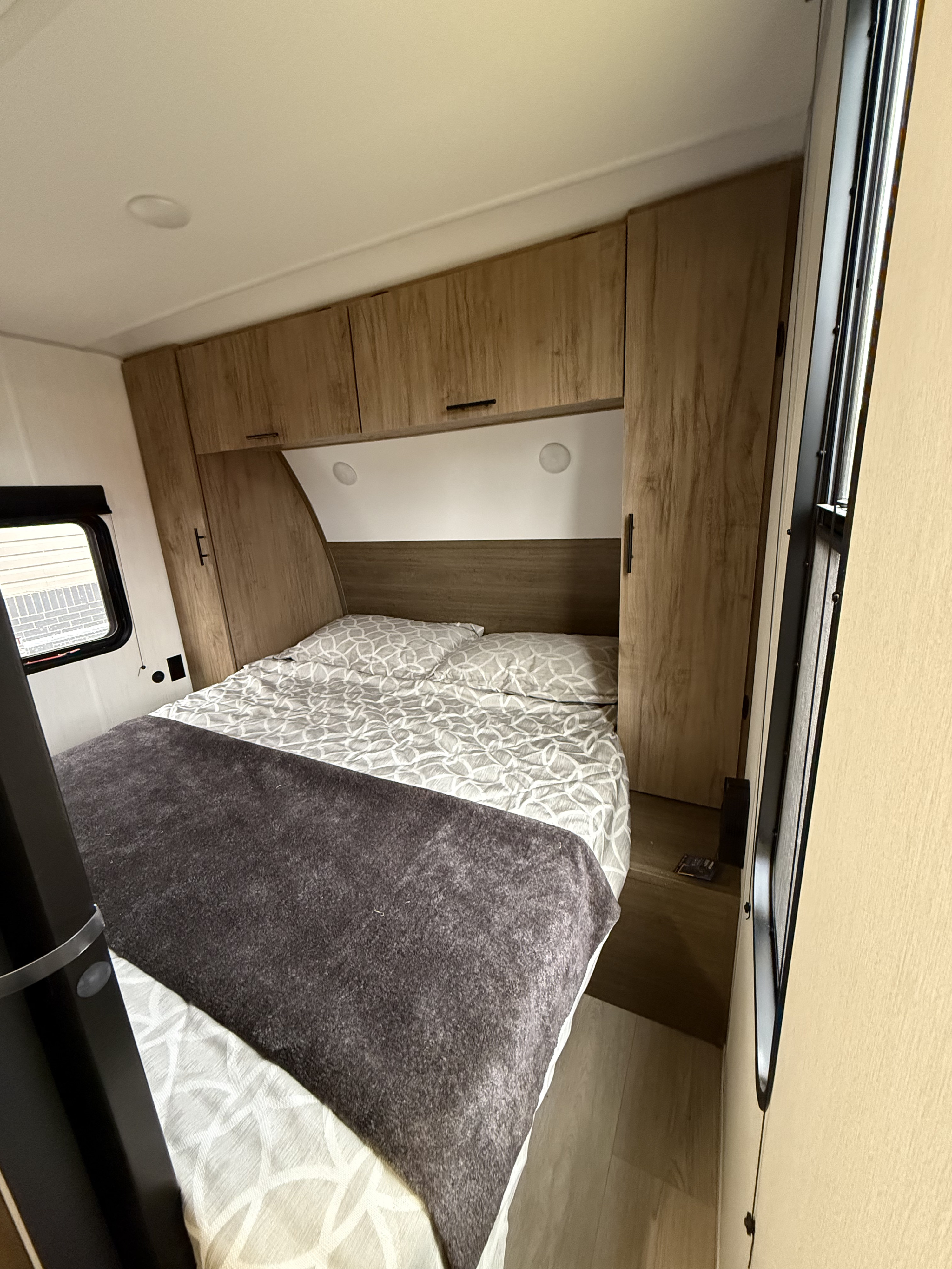 RV rental bedroom: a compact space with a cozy bed, wooden storage, and window details.. Forest River Cherokee Grey Wolf 26DBH 2025