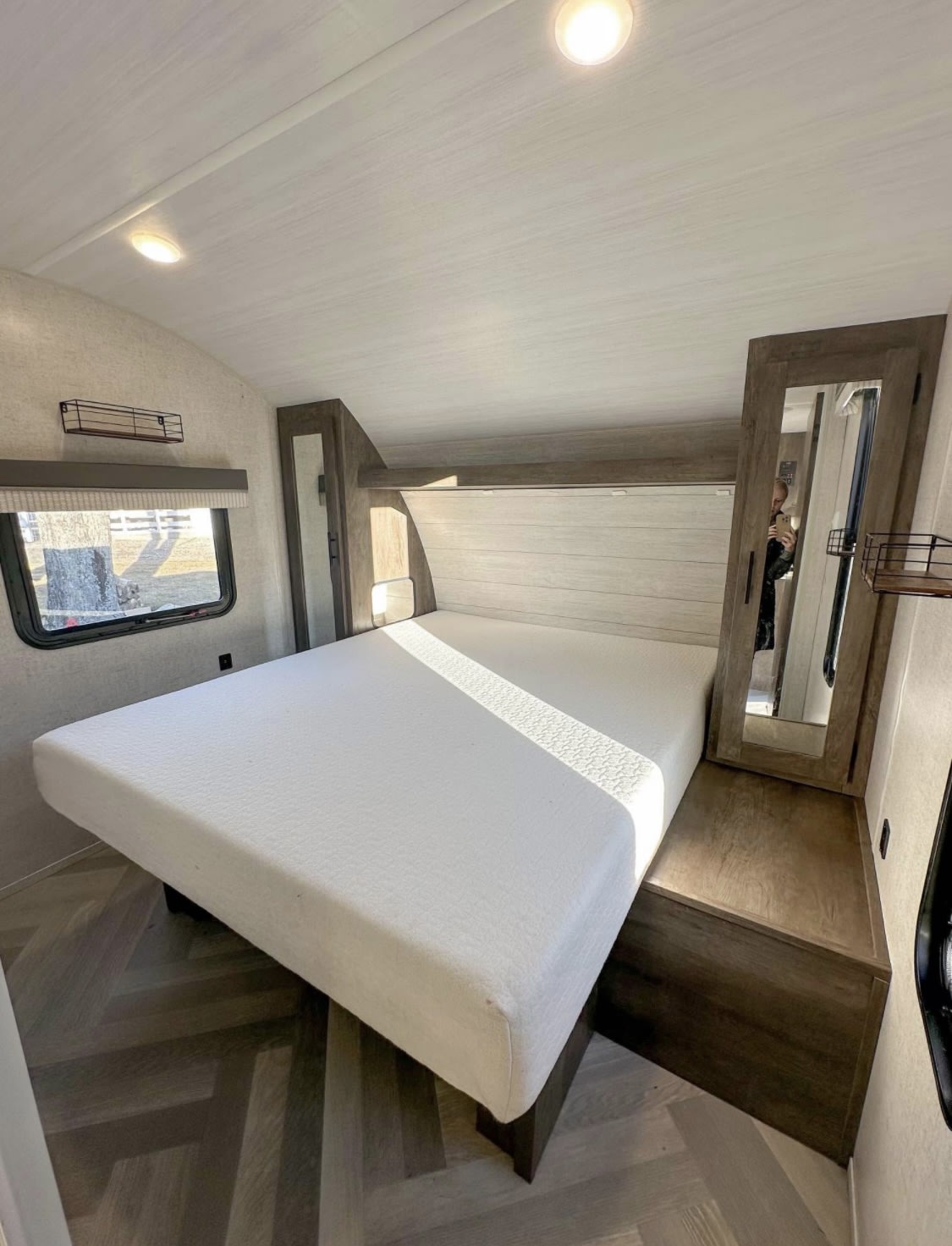 Modern RV rental bedroom featuring a versatile lift-up bed, built-in storage, and bright lighting. Ready for your next trip!. Forest River Wildwood X-Lite 2021