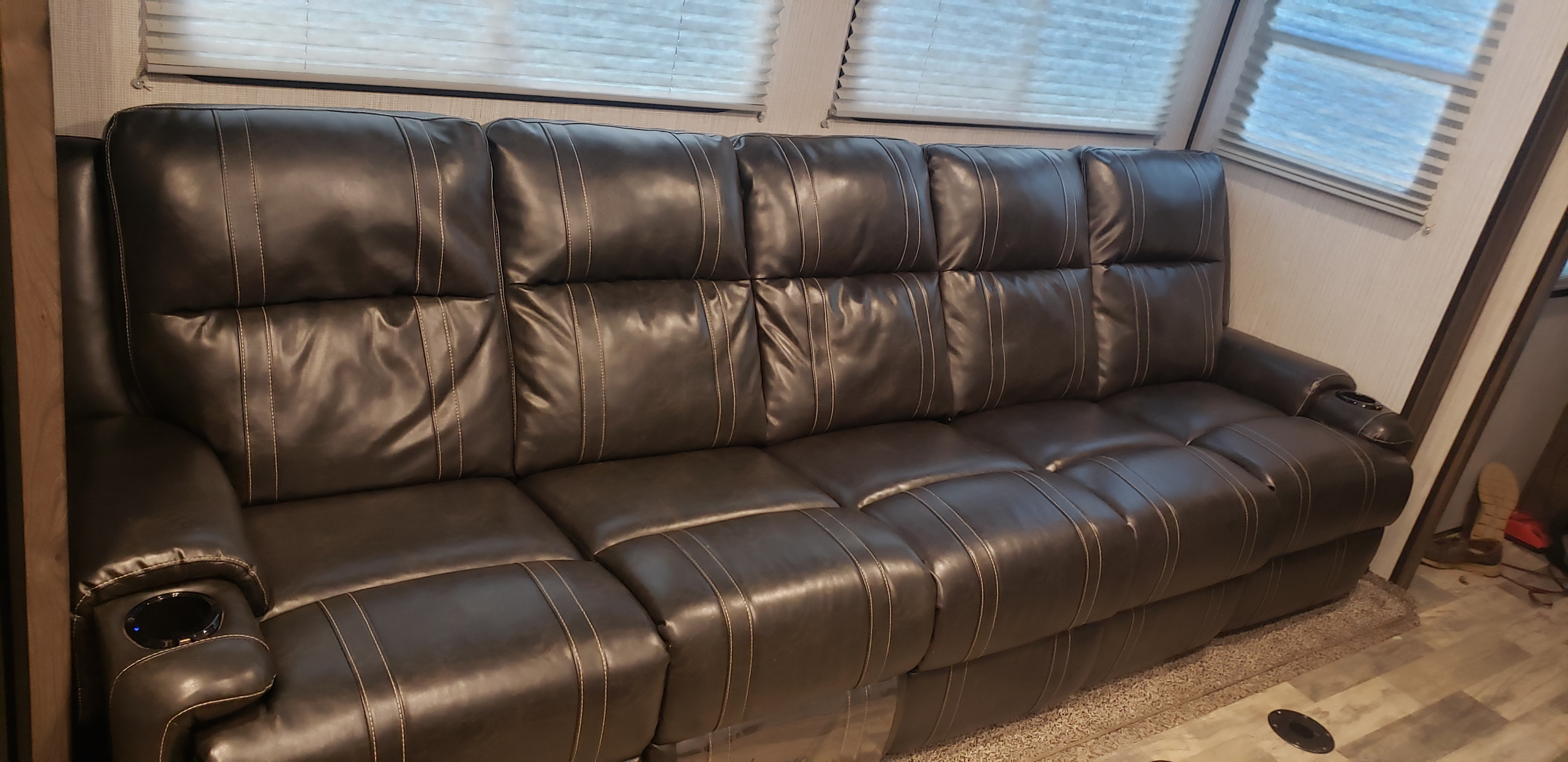 Dark brown reclining sofa with cupholders provides comfort in this RV rental.. Heartland Torque 2020
