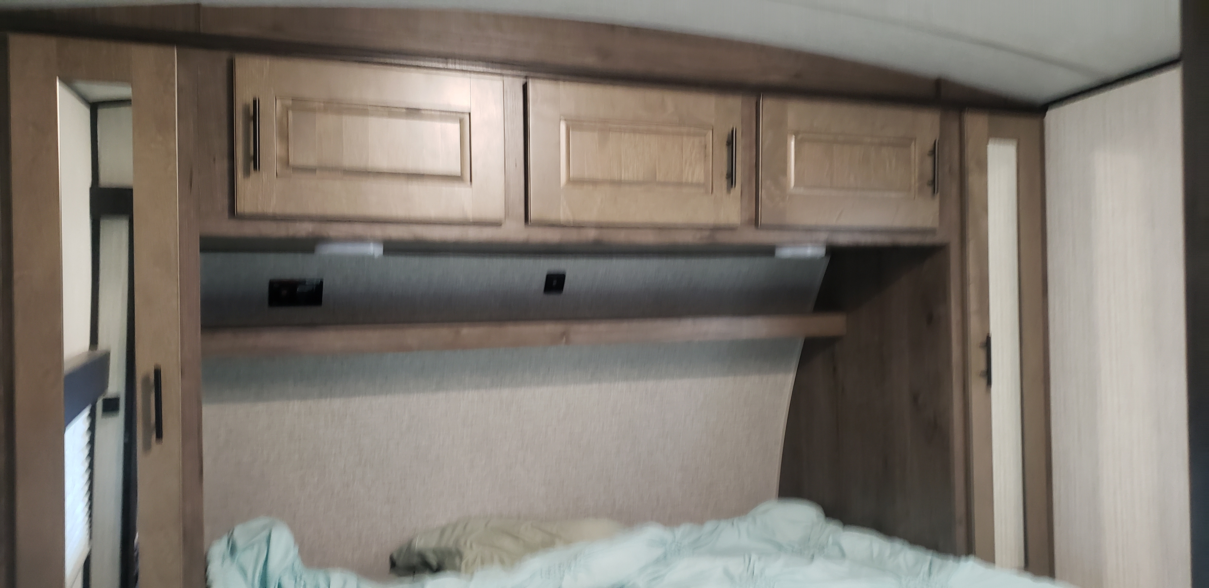 RV rental bedroom: functional design with overhead cabinets, a shelf, and mirrored side closets above the bed.. Heartland Torque 2020