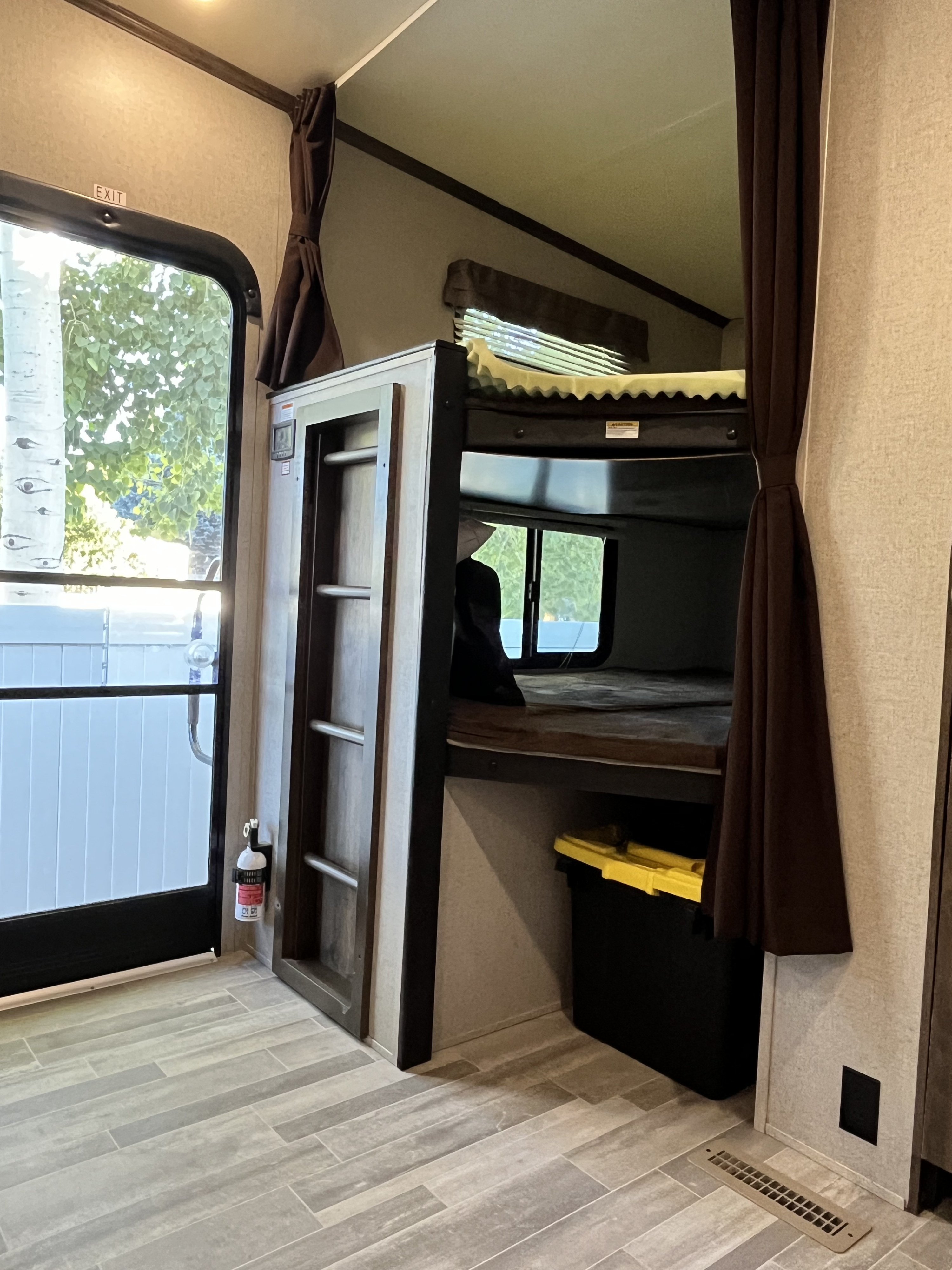 RV rental: Interior view of bunk beds, an exit door with a fire extinguisher, and storage, all on wood-look flooring.. Dutchmen Astoria 2018