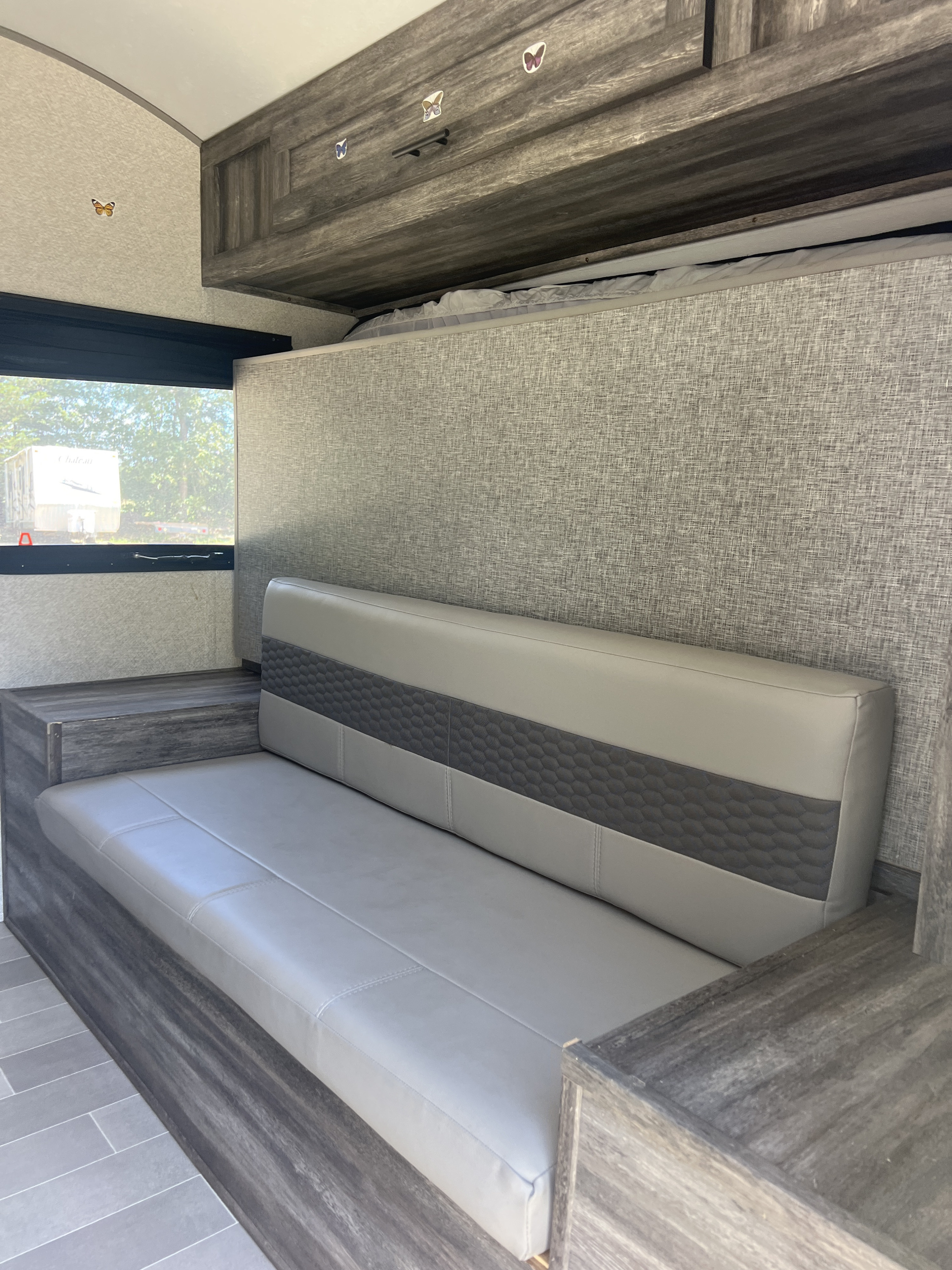 RV rental: modern gray dinette sofa with textured back, wood-grain cabinets & floor. Bright interior with window view.. Forest River Salem FSX 2021