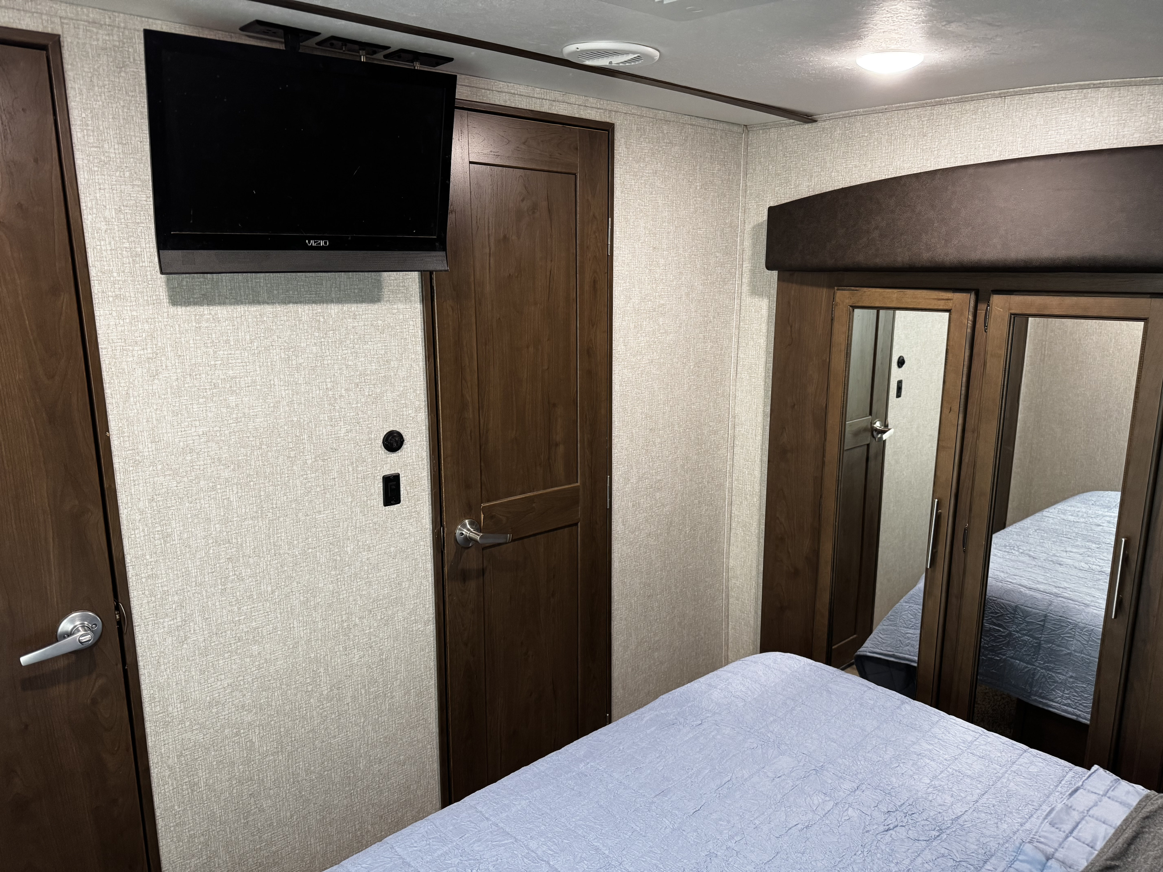 Cozy RV rental bedroom with a mounted TV, bed, and mirrored closet. Perfect for your next adventure.. Keystone RV Cougar 2019