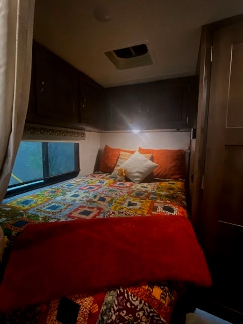 Cozy RV rental bedroom with colorful bed, window, and overhead storage. Ideal for adventurers.. Forest River Coachmen Prism 2017