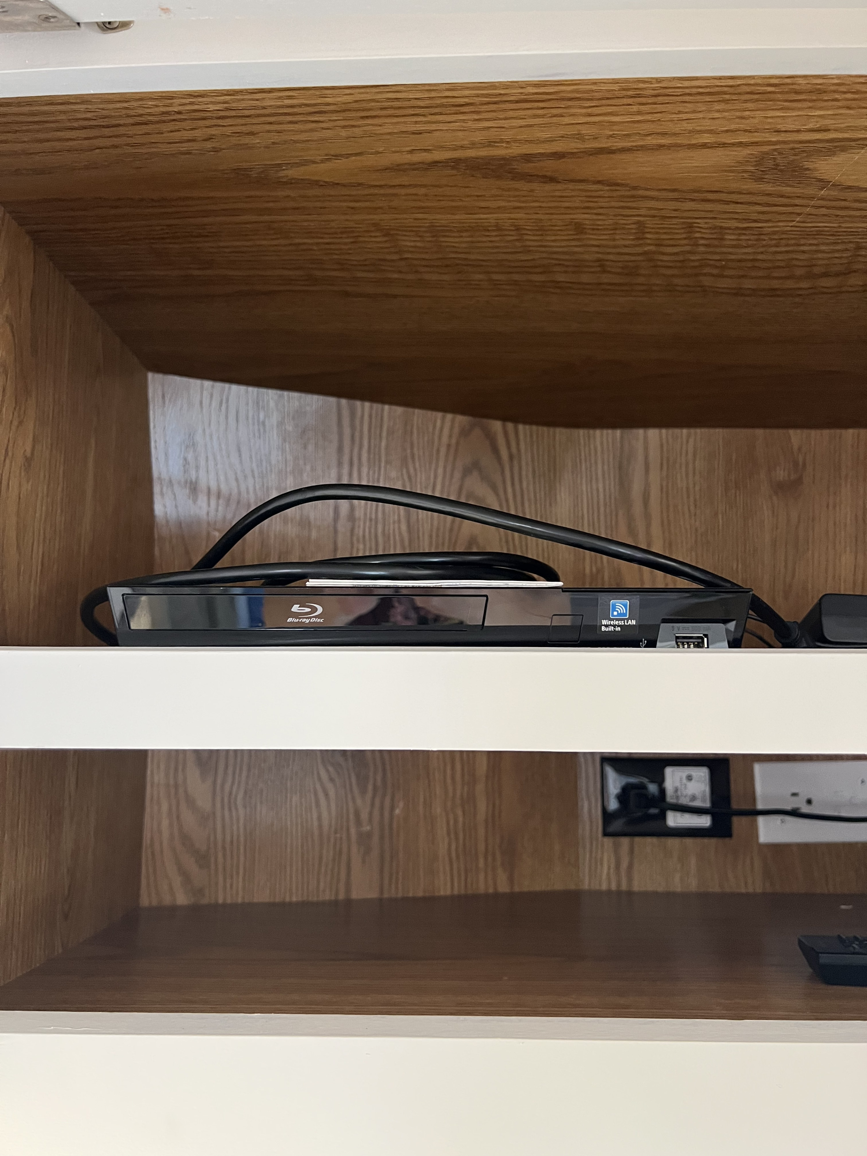 RV rental: A Blu-ray player with built-in Wi-Fi and cables in a wooden cabinet, providing entertainment with visible power outlets.. Fleetwood Bounder 2005