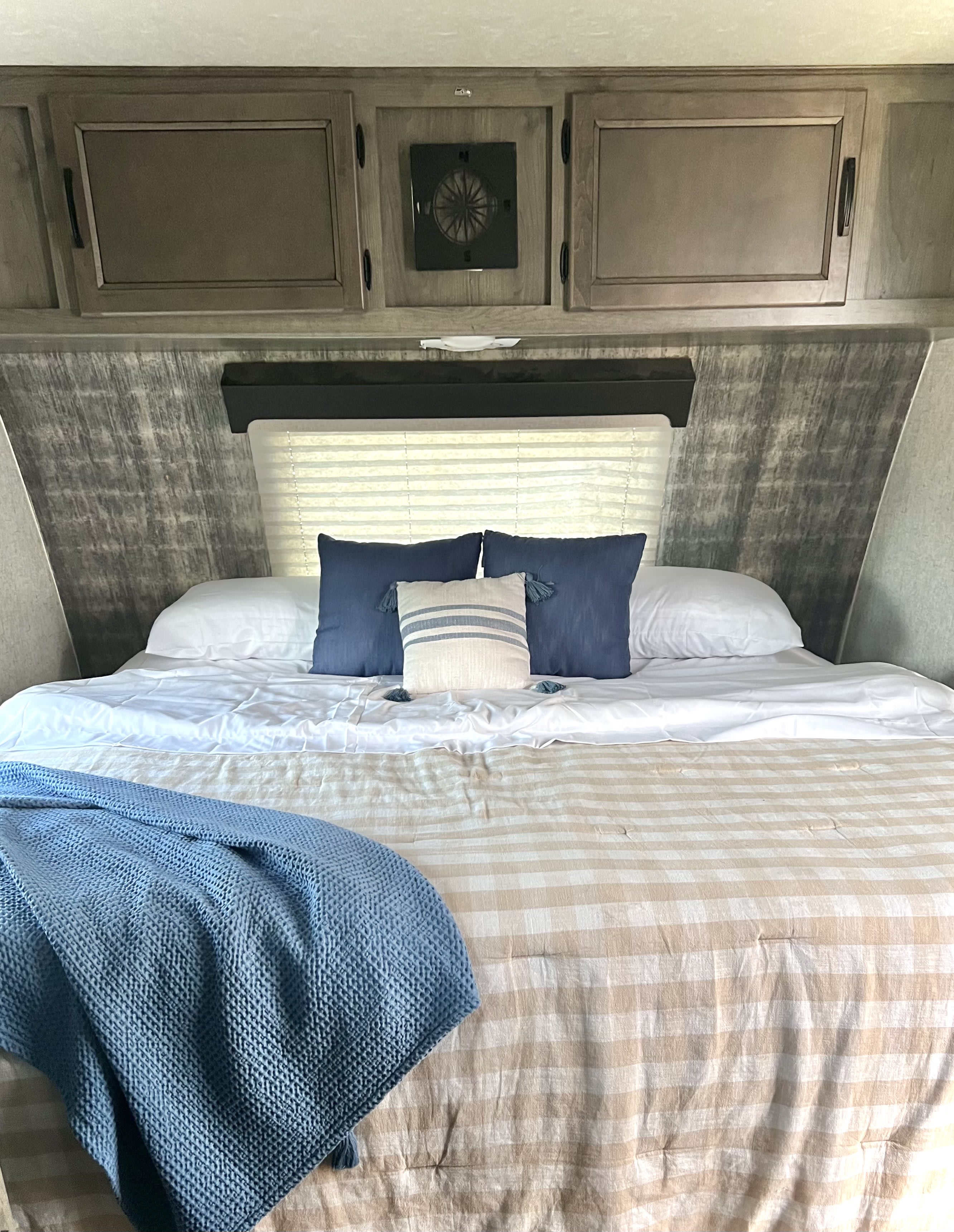 Step into comfort! This RV rental bedroom features blue/beige bedding, overhead storage, and a unique compass fan.. Coachmen 226 BH 2019
