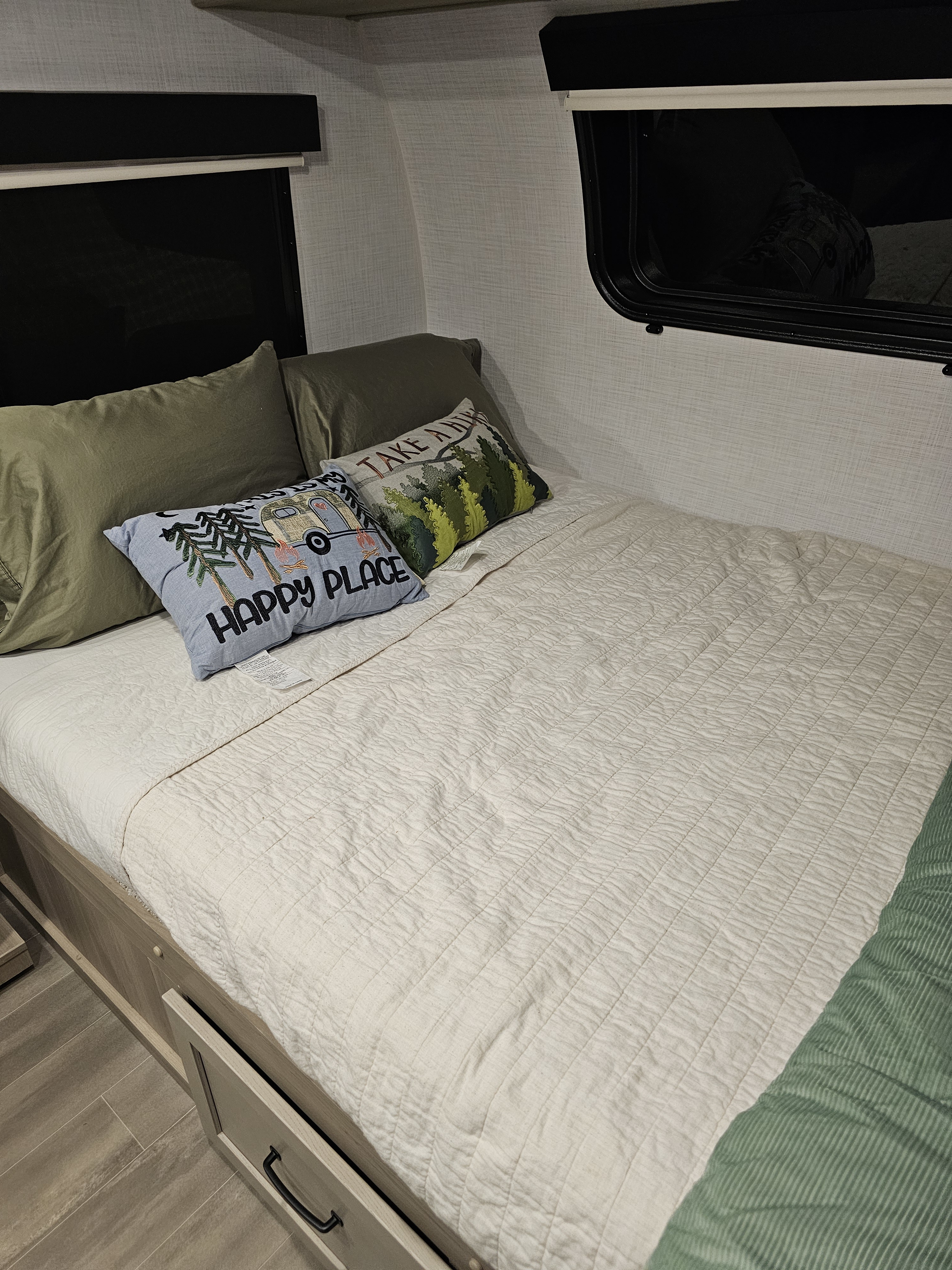 Cozy RV rental bedroom featuring camping-themed pillows, under-bed storage, and windows for your travel adventures.. Forest River Flagstaff E-Pro 2024
