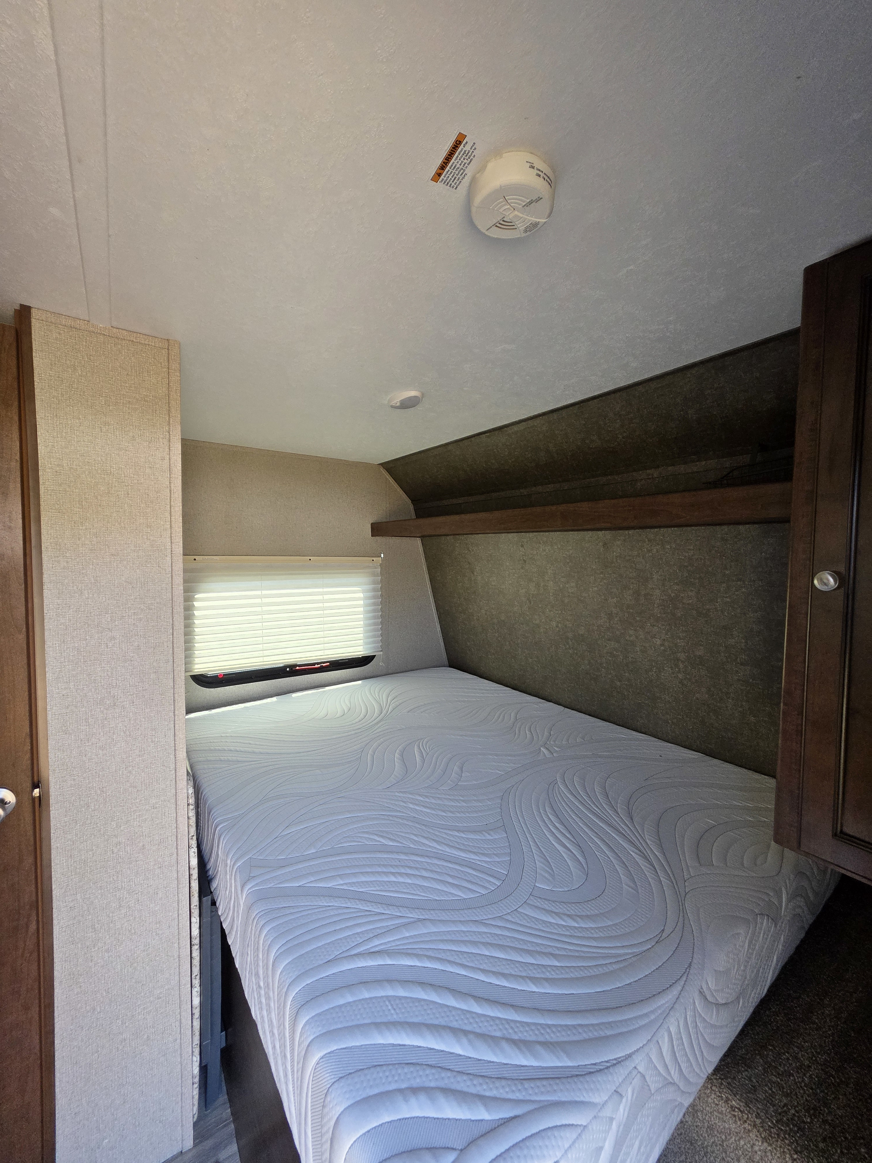 This RV rental offers a compact bedroom with a pristine mattress, window, and essential safety features like a smoke detector.. Keystone RV Hideout LHS Mini 2017