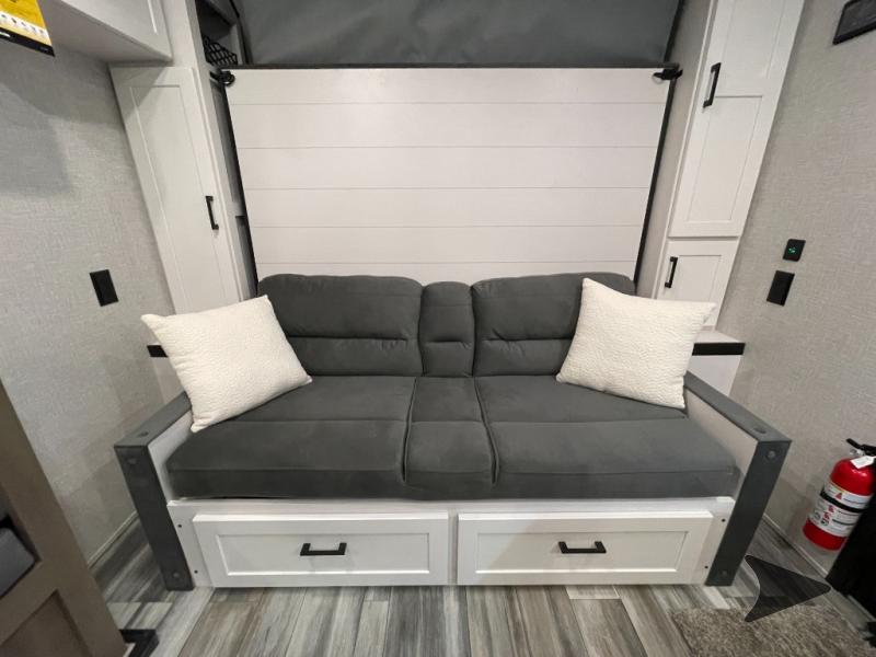 RV rental: Compact living space features a gray sofa, storage drawers below, and a fold-down wall bed.. JAYCO JAY FLIGHT SLX 197MBW BAJA-G 2025