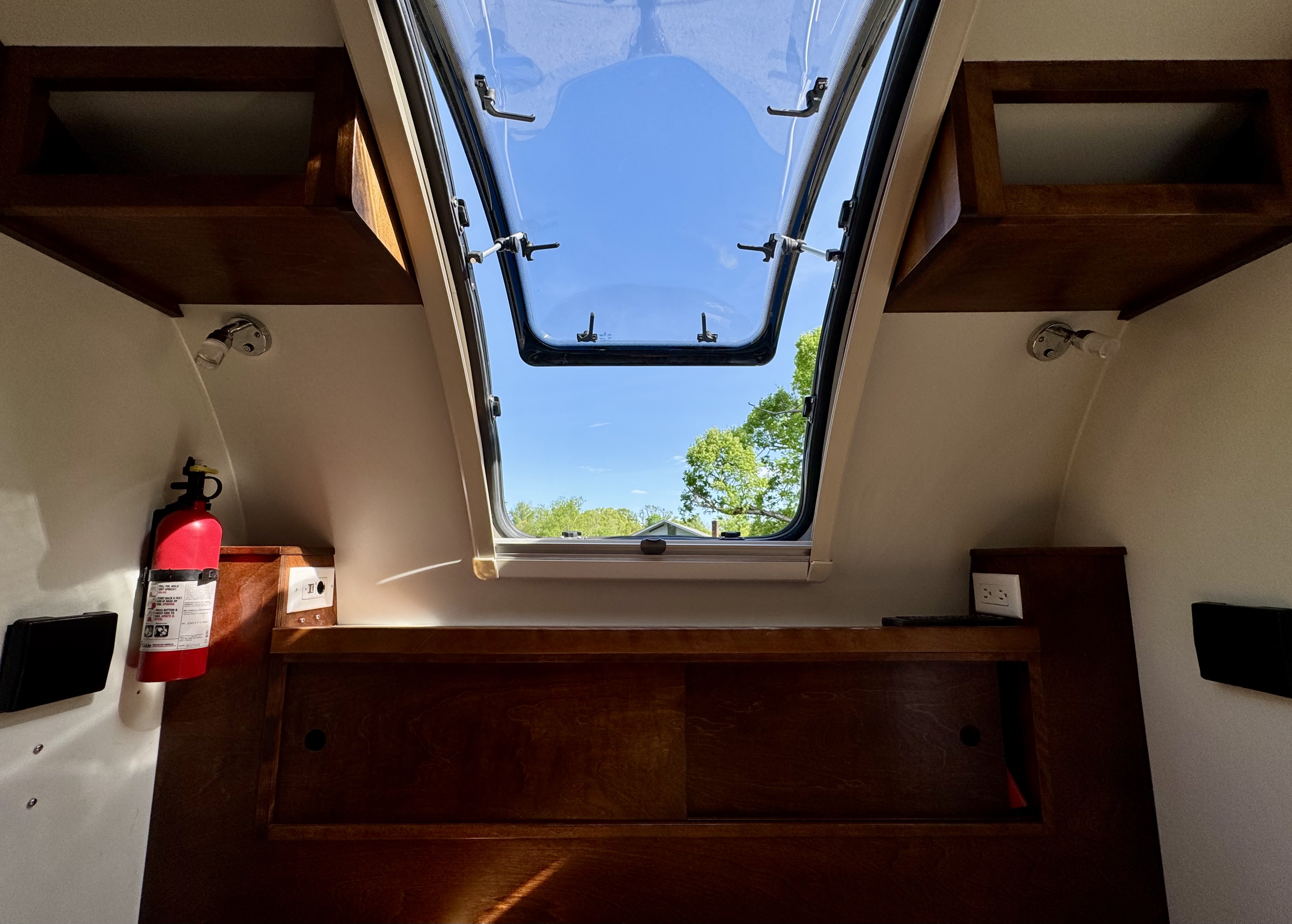 Cozy RV rental interior. Features include a large open skylight, wooden cabinetry, and essential safety gear.. nuCamp T@G 2018