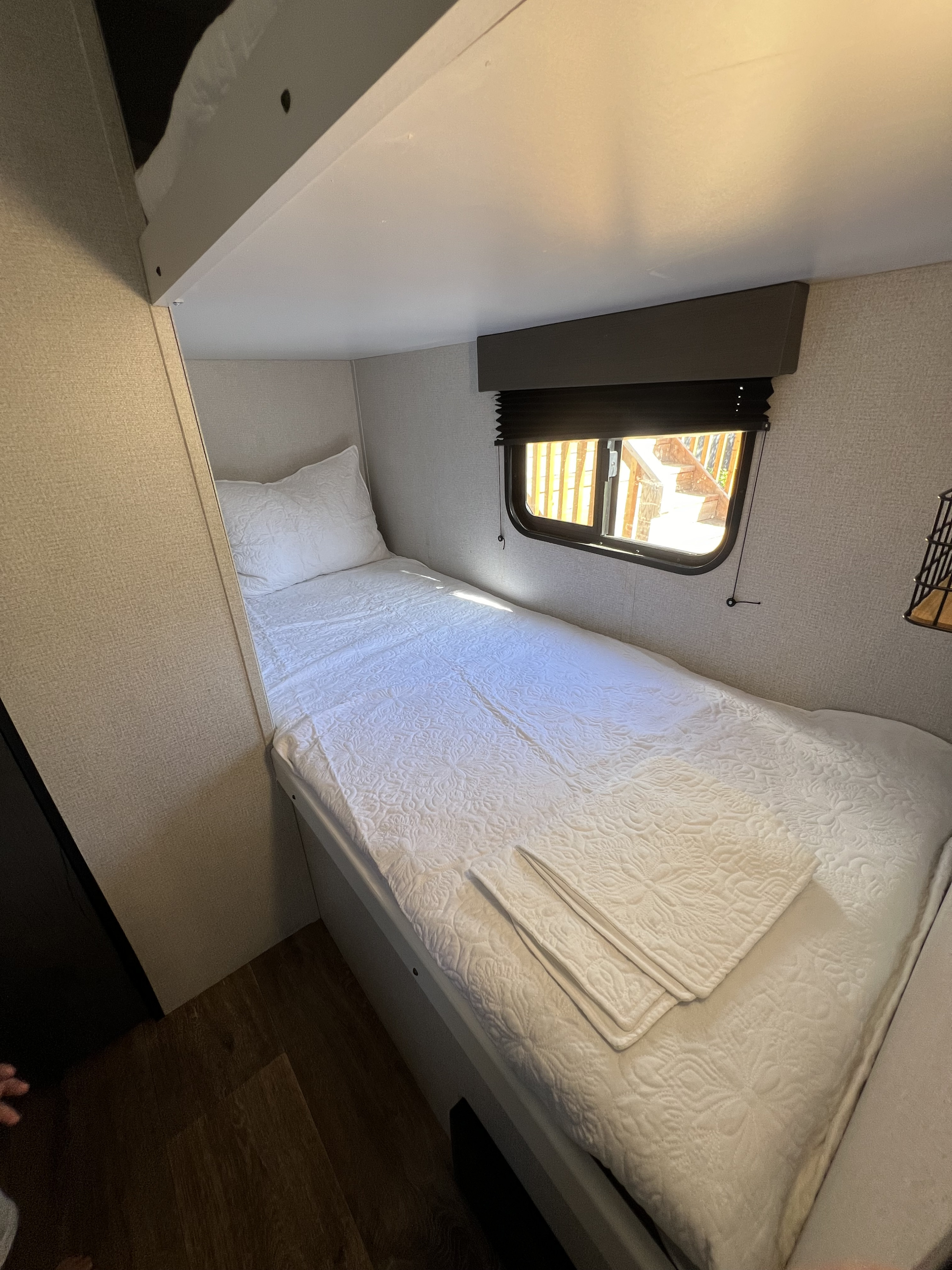 Cozy RV rental bunk bedroom with a single bed, white quilted bedding, and a window providing natural light.. Keystone RV Hideout 2021