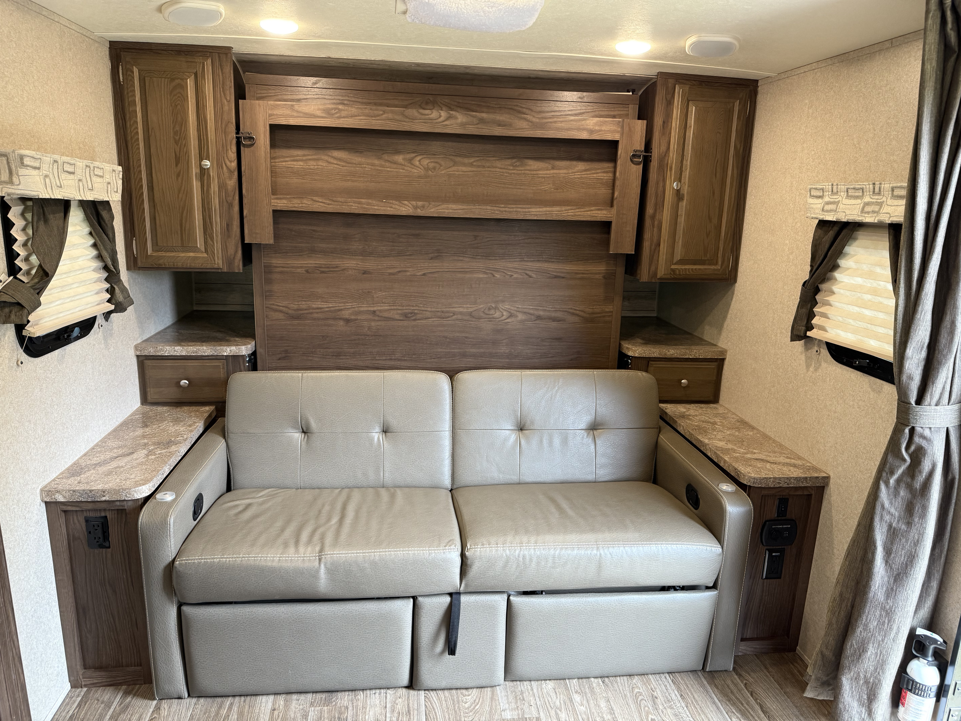 Cozy RV rental interior featuring a light sofa bed, wood cabinets, side tables with power outlets, and warm lighting.. Forest River Flagstaff Micro Lite 2019