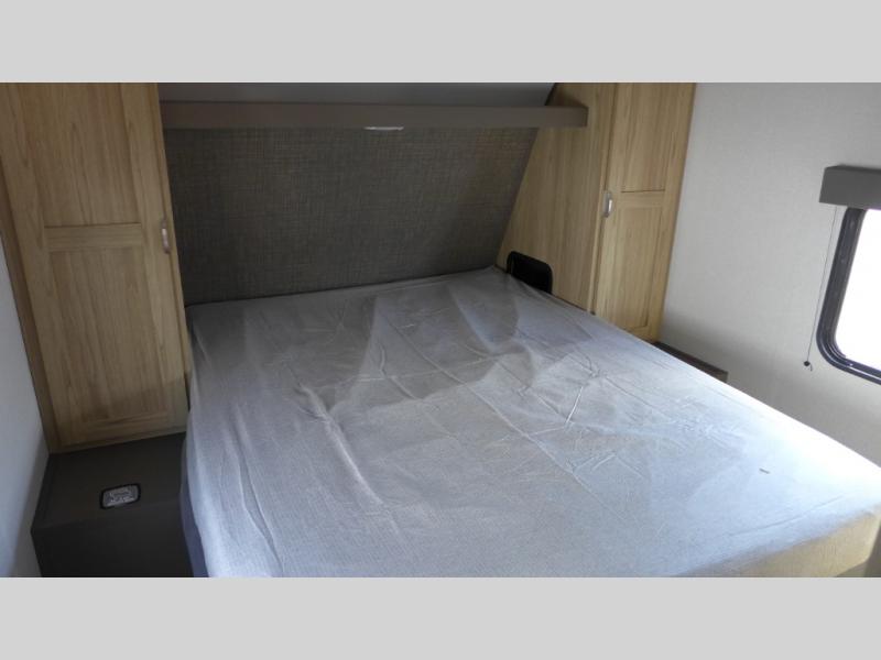 RV rental bedroom featuring a large bed, framed by light wood cabinets on each side, and a window on the right.. Avenir 32bh 2025