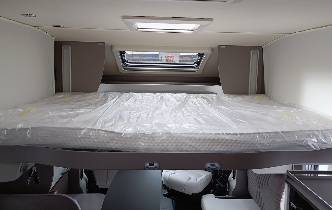 Spacious overhead bed in a clean RV rental motorhome, highlighting the bright interior and living area below.. BURSTNER Lyséo TD 736 Privilège 2023
