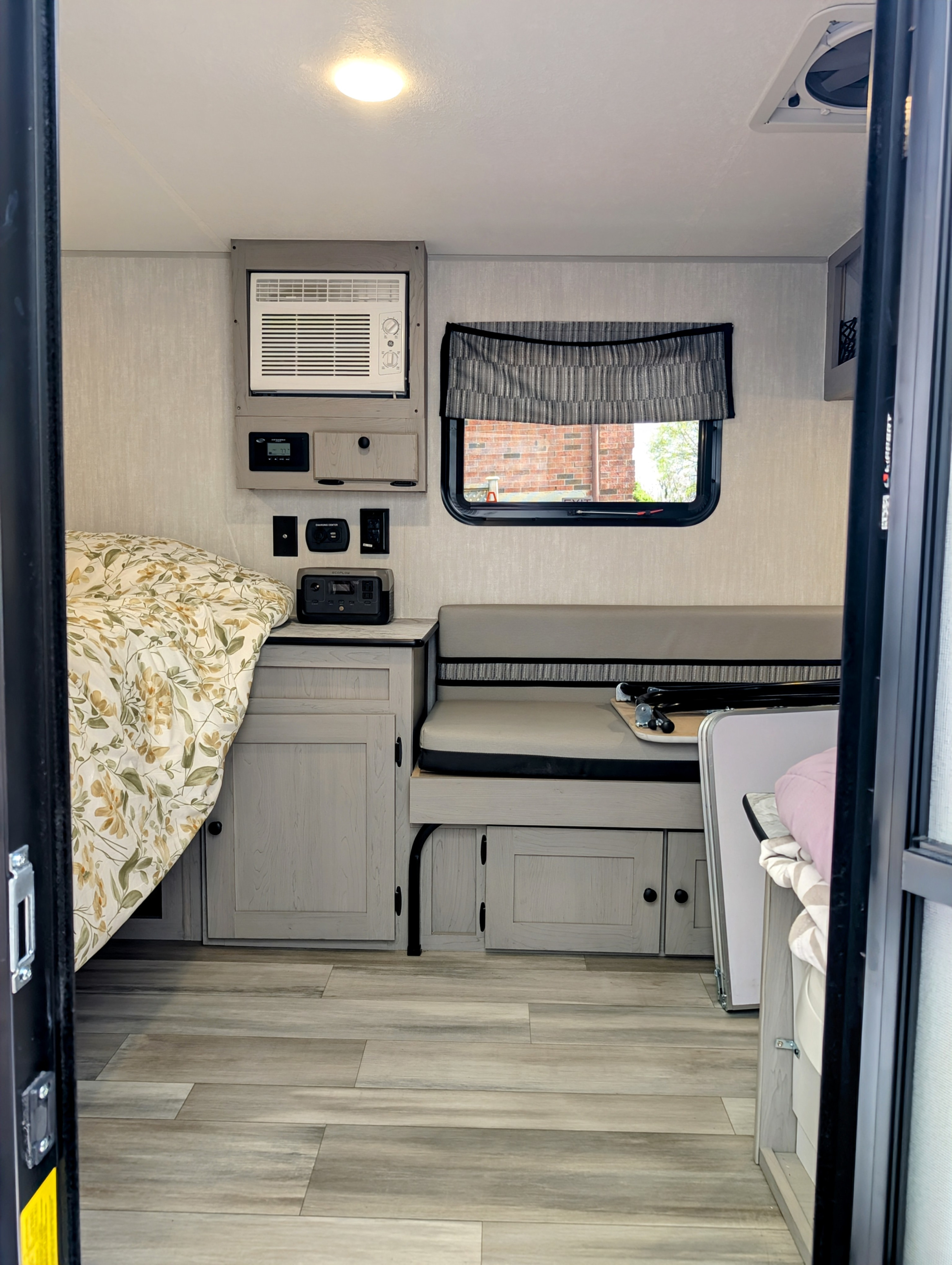 Cozy RV rental interior featuring a floral bed, compact dinette seating, and essential controls, ideal for travel.. Coachmen Viking 1200ROK 2025