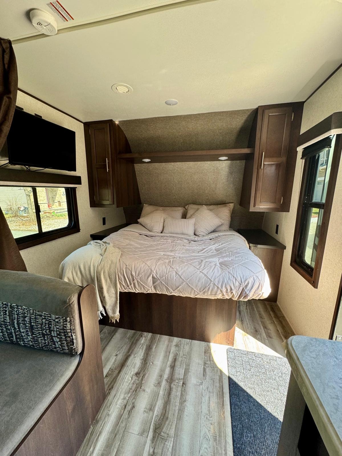 Cozy RV rental bedroom featuring a comfortable bed, overhead storage, TV, and light wood-look flooring.. Jayco Jay Flight SLX 2019