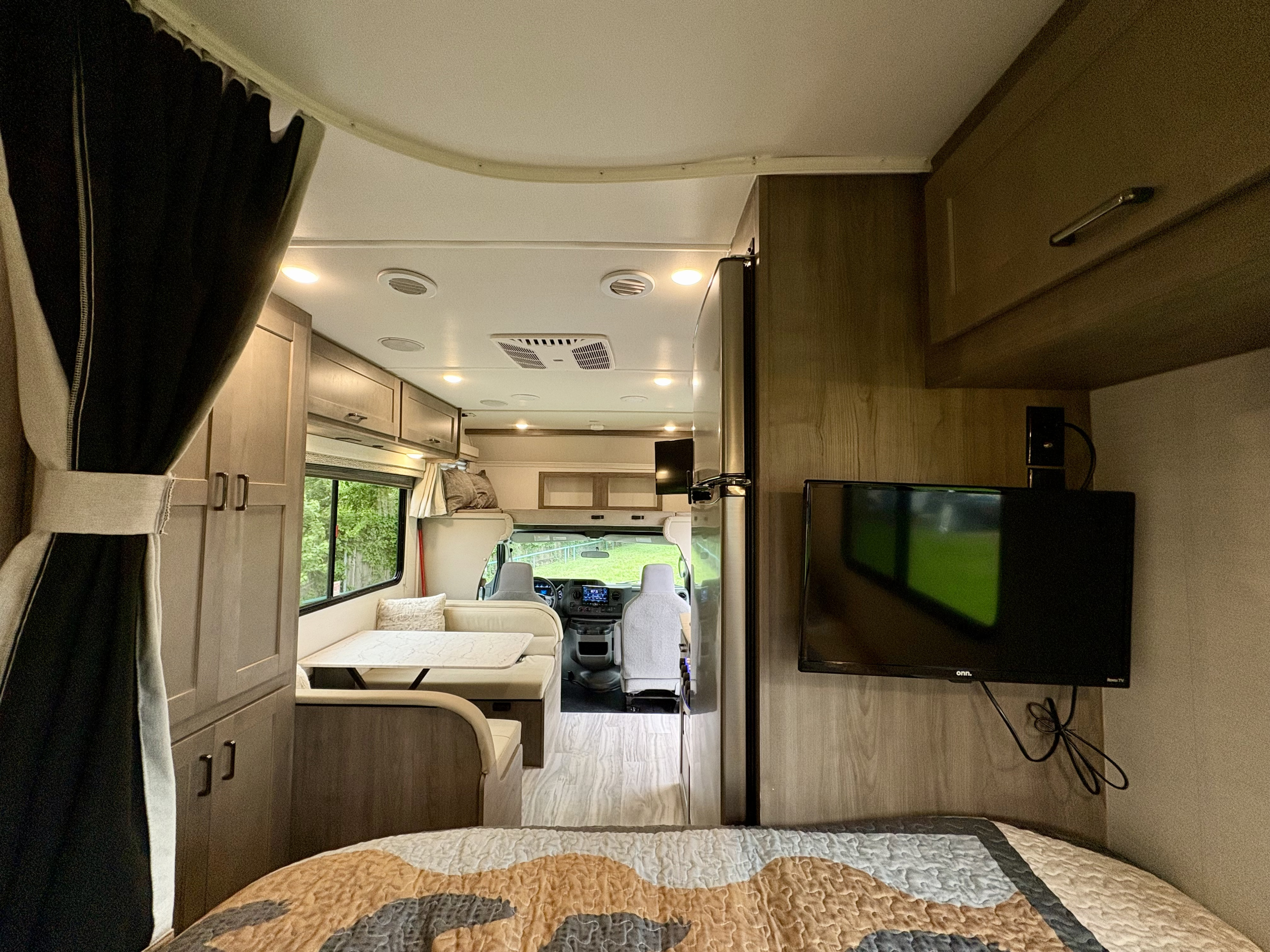 Spacious RV rental interior: from the bed, view a dinette, kitchen, and cockpit, offering comfortable travel.. Gulf Stream Conquest 2025