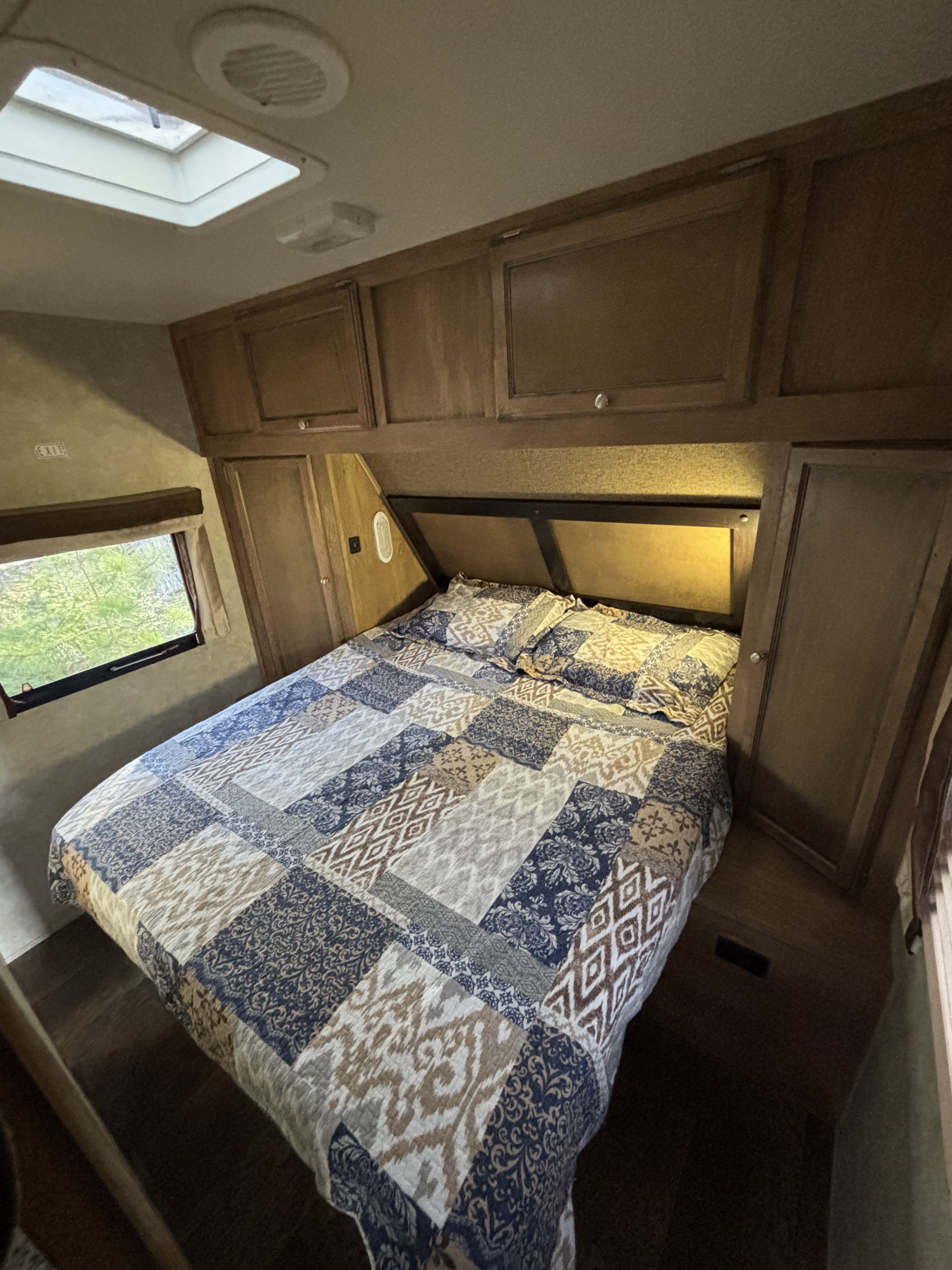 Cozy RV rental bedroom with a patchwork quilt, overhead storage, window view, and skylight.. Gulf Stream Gulf Breeze Ultra Lite 2016