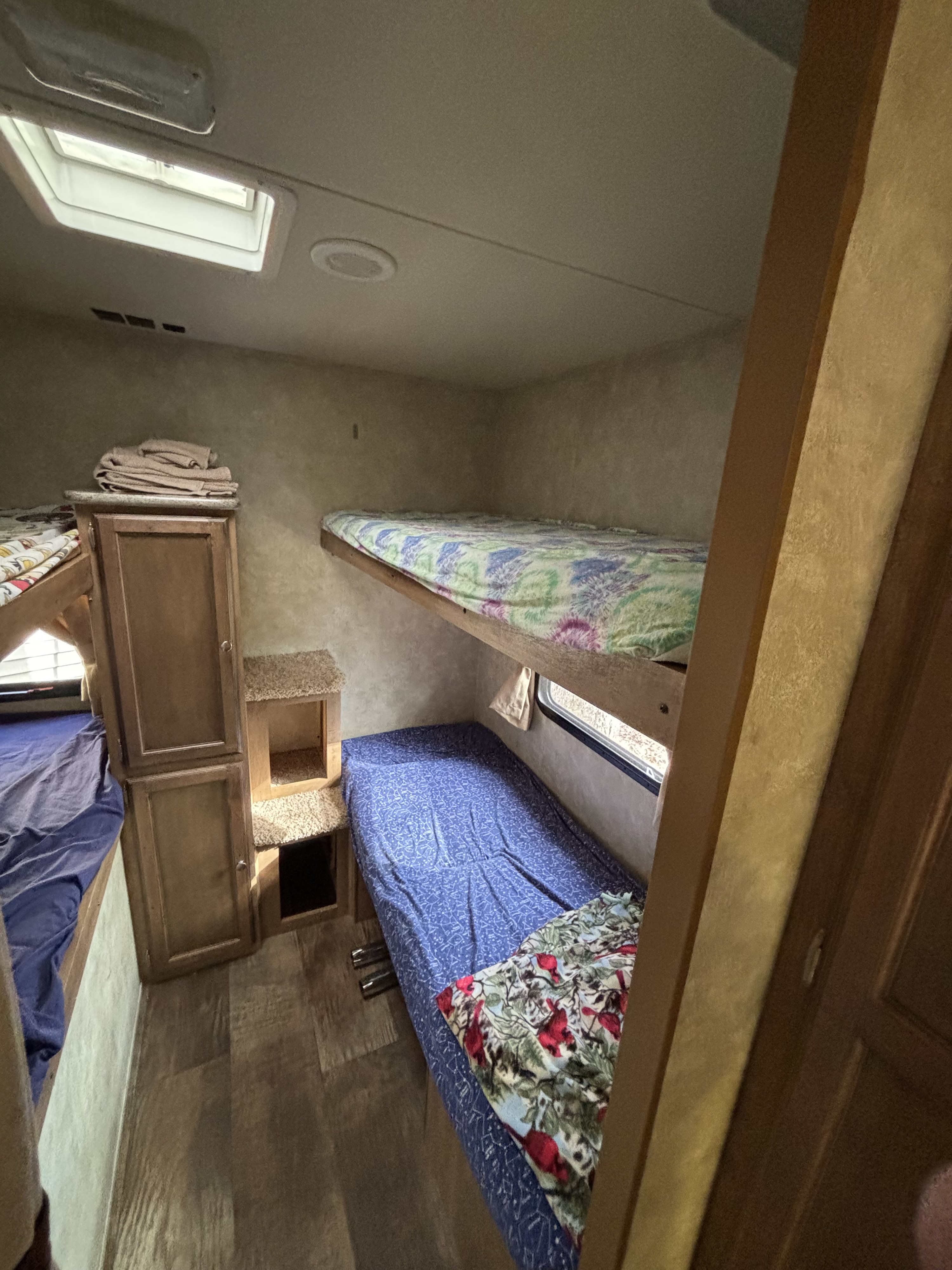 An rv rental bunk room with three beds, ample storage cabinets, a bright skylight, and wood-look flooring. Ready for travelers.. Gulf Stream Gulf Breeze Ultra Lite 2016