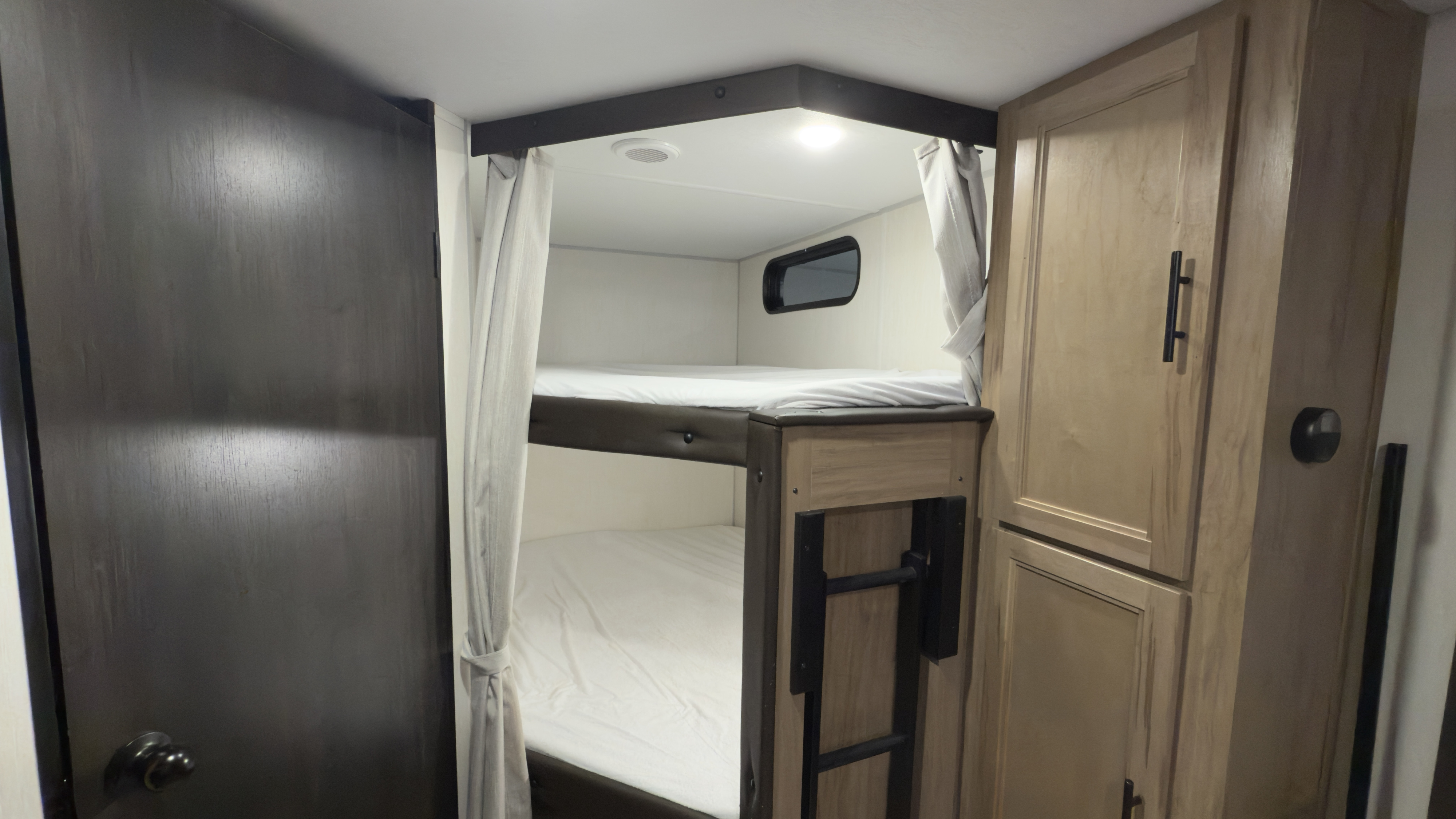 Cozy RV rental interior with comfortable bunk beds, storage cabinets, and privacy curtains, perfect for family adventures.. Forest River Grey Wolf 23DBH 2025