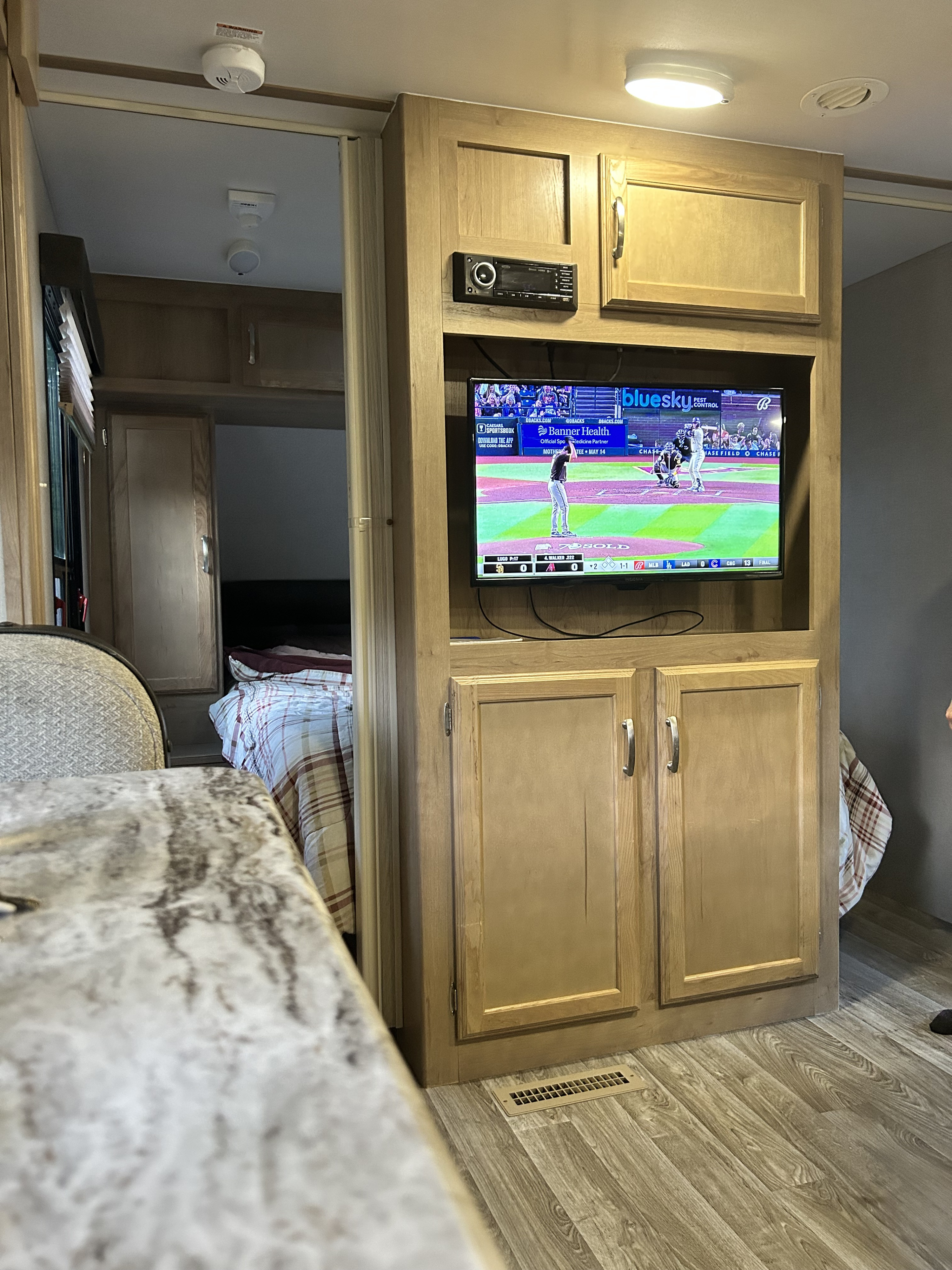 Enjoying a baseball game on TV in an RV rental's cozy living space, complete with built-in entertainment and bedroom access.. Winnebago Minnie 2455BHS 2020