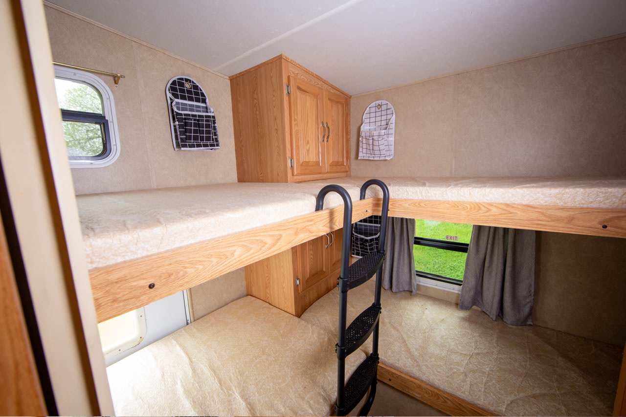 Compact RV rental interior shows two bunk beds with a ladder, cabinet, and windows, ideal for a comfortable sleeping setup.. Crossroads RV Cruiser 2006