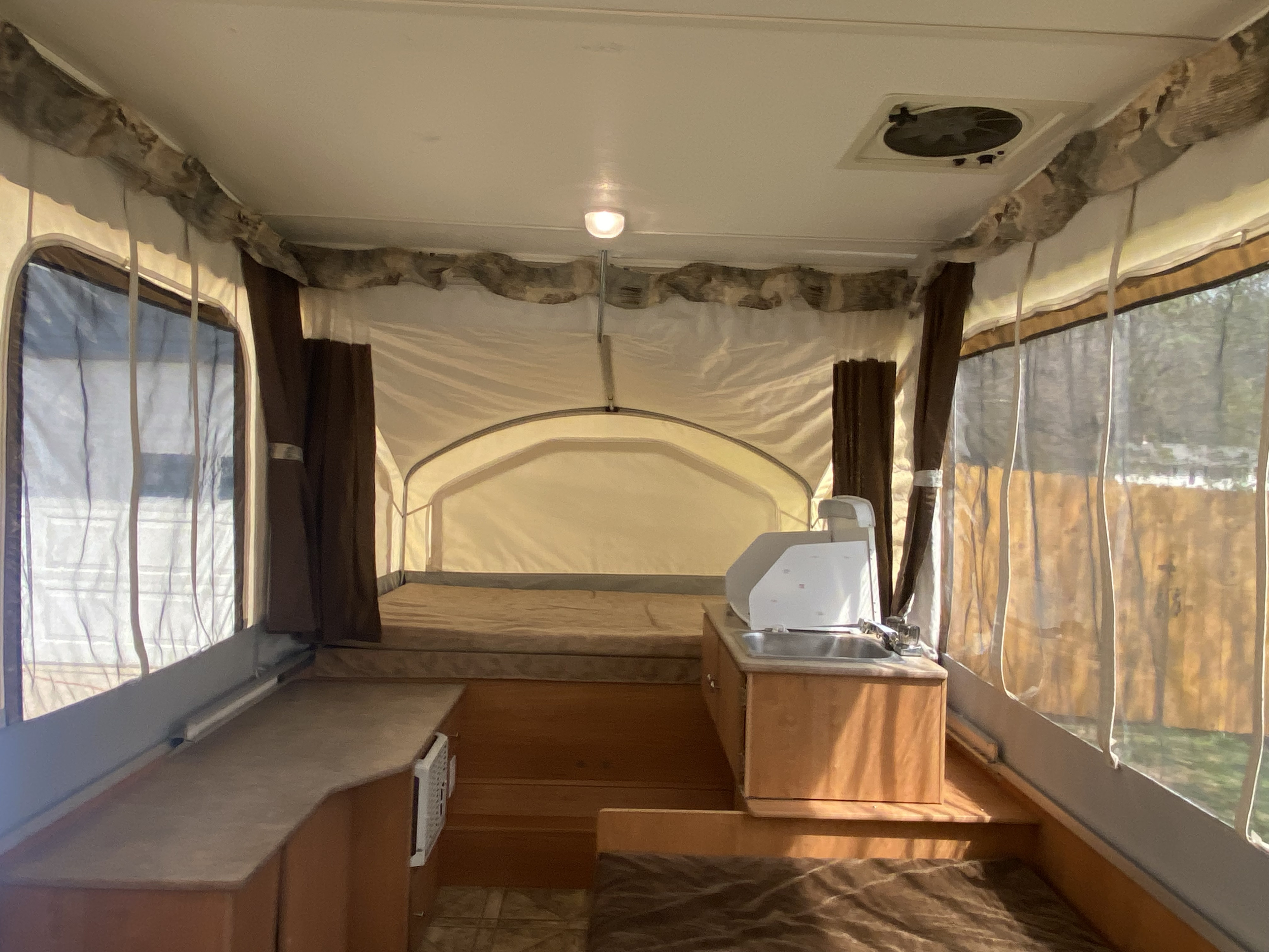 Interior of an RV rental pop-up camper, featuring beds, kitchen sink, and AC unit.. Coachmen Clipper 2010