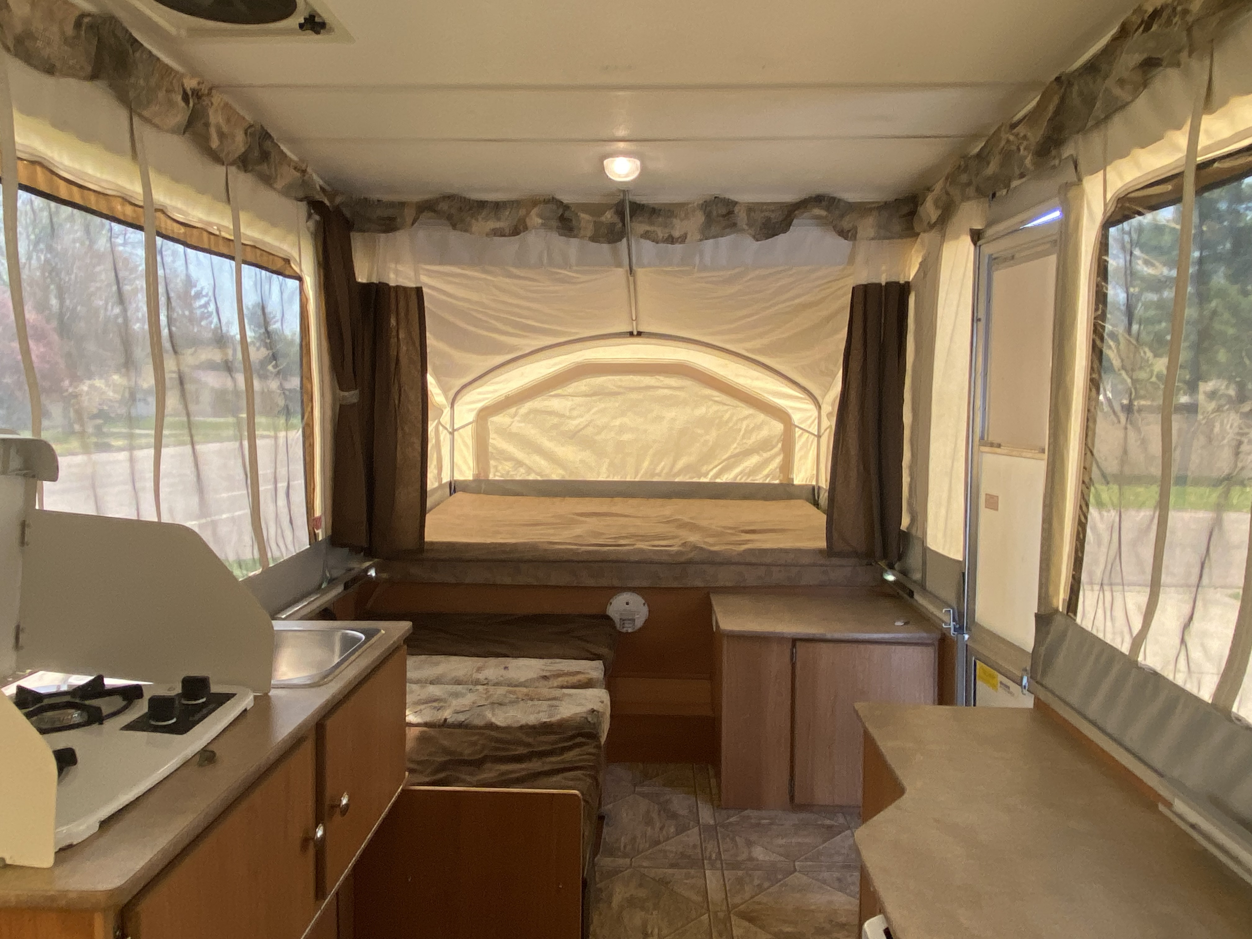 Inside an RV rental pop-up camper, featuring beds, a kitchen, and dining area for comfortable camping.. Coachmen Clipper 2010