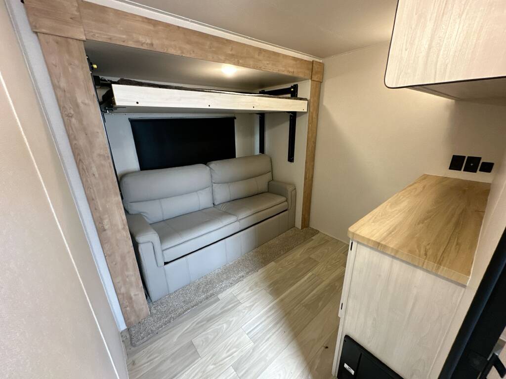 Cozy RV rental interior featuring a versatile sofa, pull-down bunk bed, and stylish wood accents, perfect for compact living.. Crusader 382mbh 2023