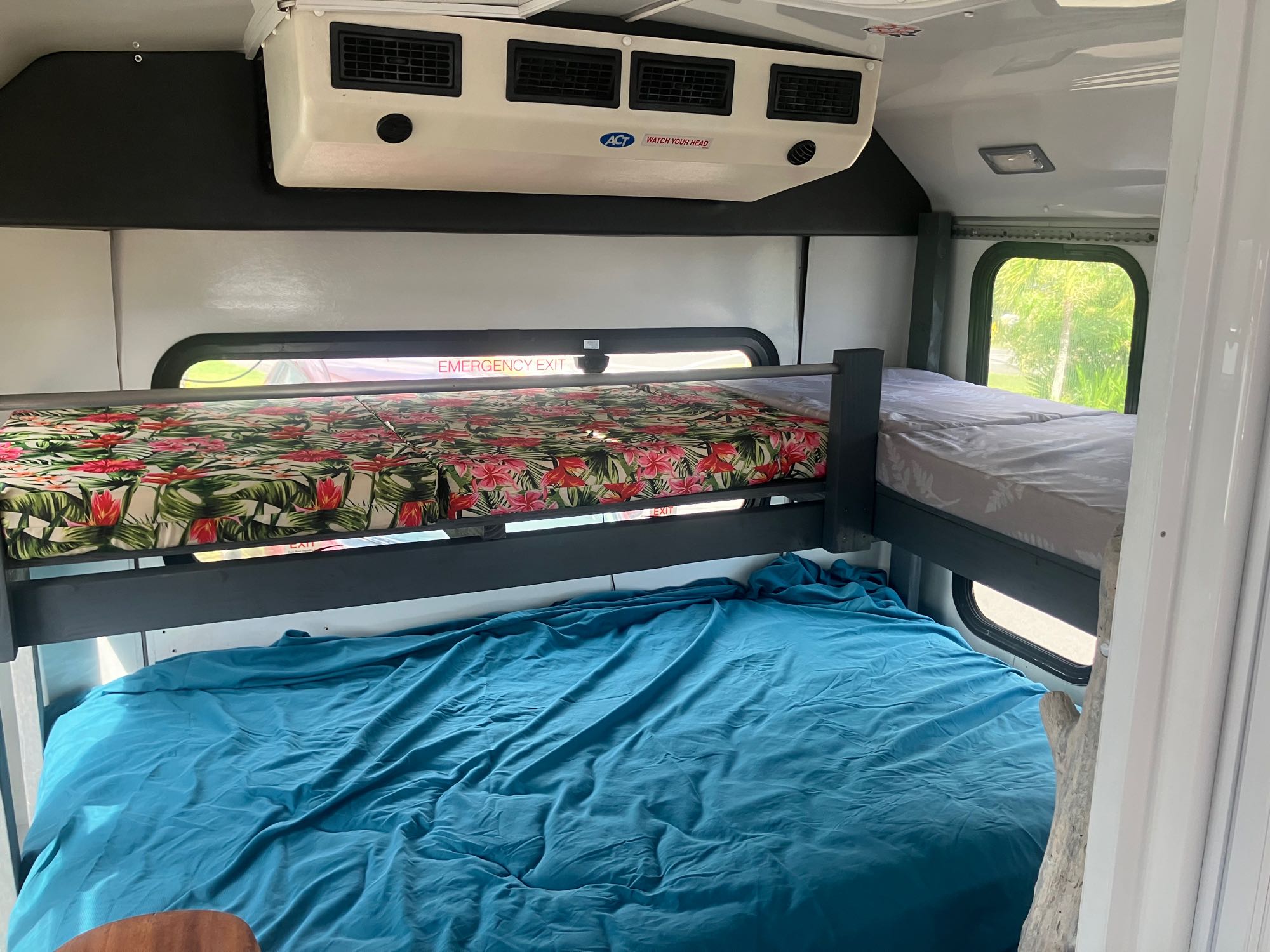Cozy RV rental interior with multiple bunk beds. Ideal for a compact sleeping area in this unique bus conversion.. Ford E450 2014