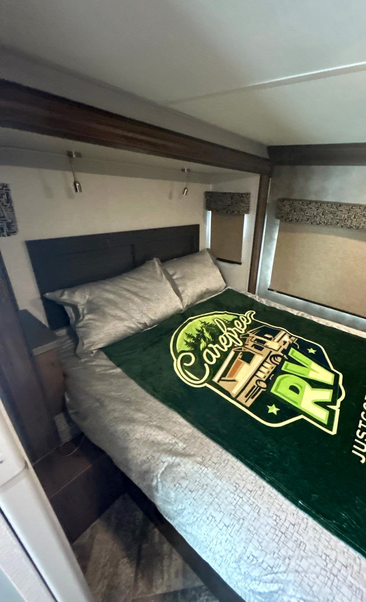 Cozy RV rental bedroom with a comfy bed, headboard, and a unique 'Carefree RV' blanket.. Forest River Sunseeker 2021
