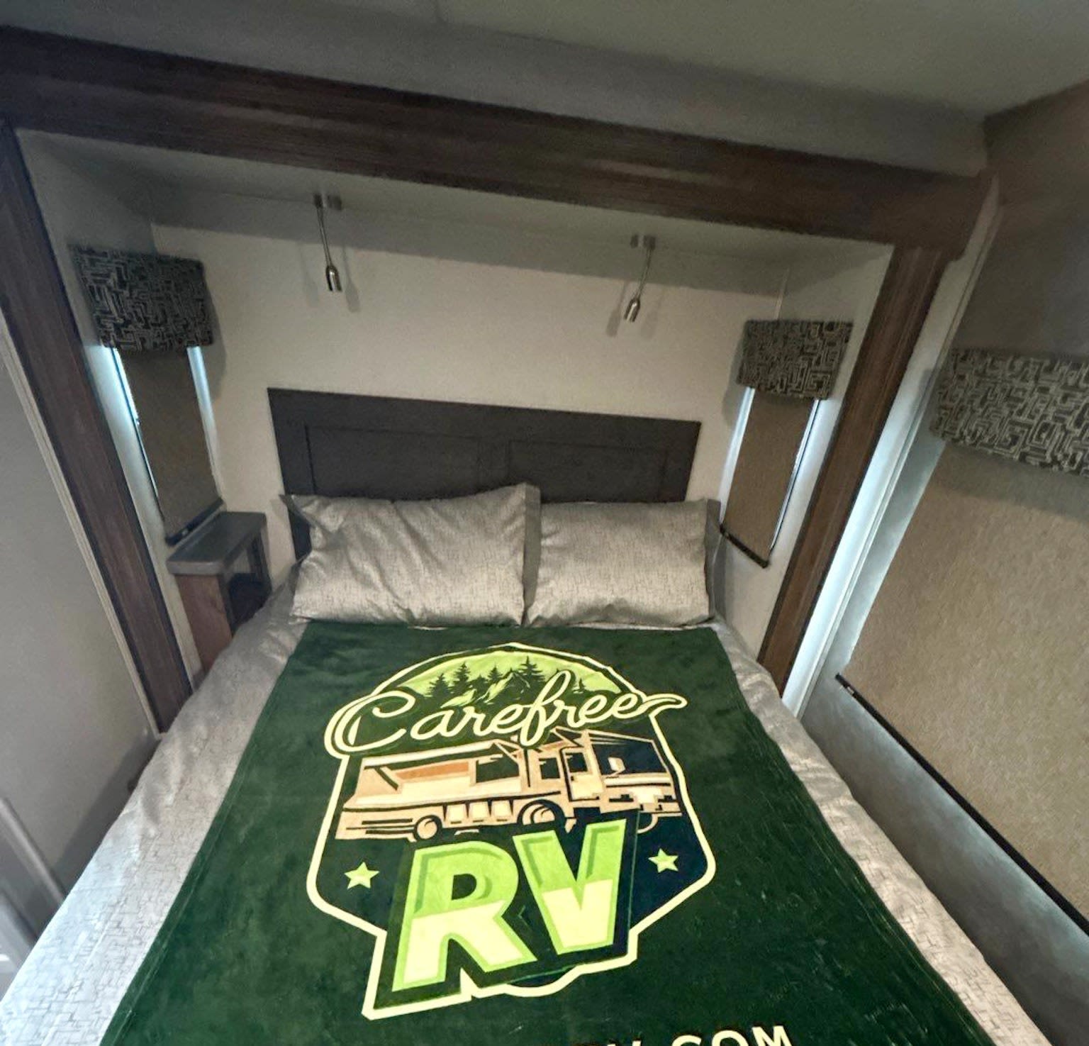 Cozy RV rental bedroom featuring a comfortable bed, pillows, and a "Carefree RV" blanket.. Forest River Sunseeker 2021