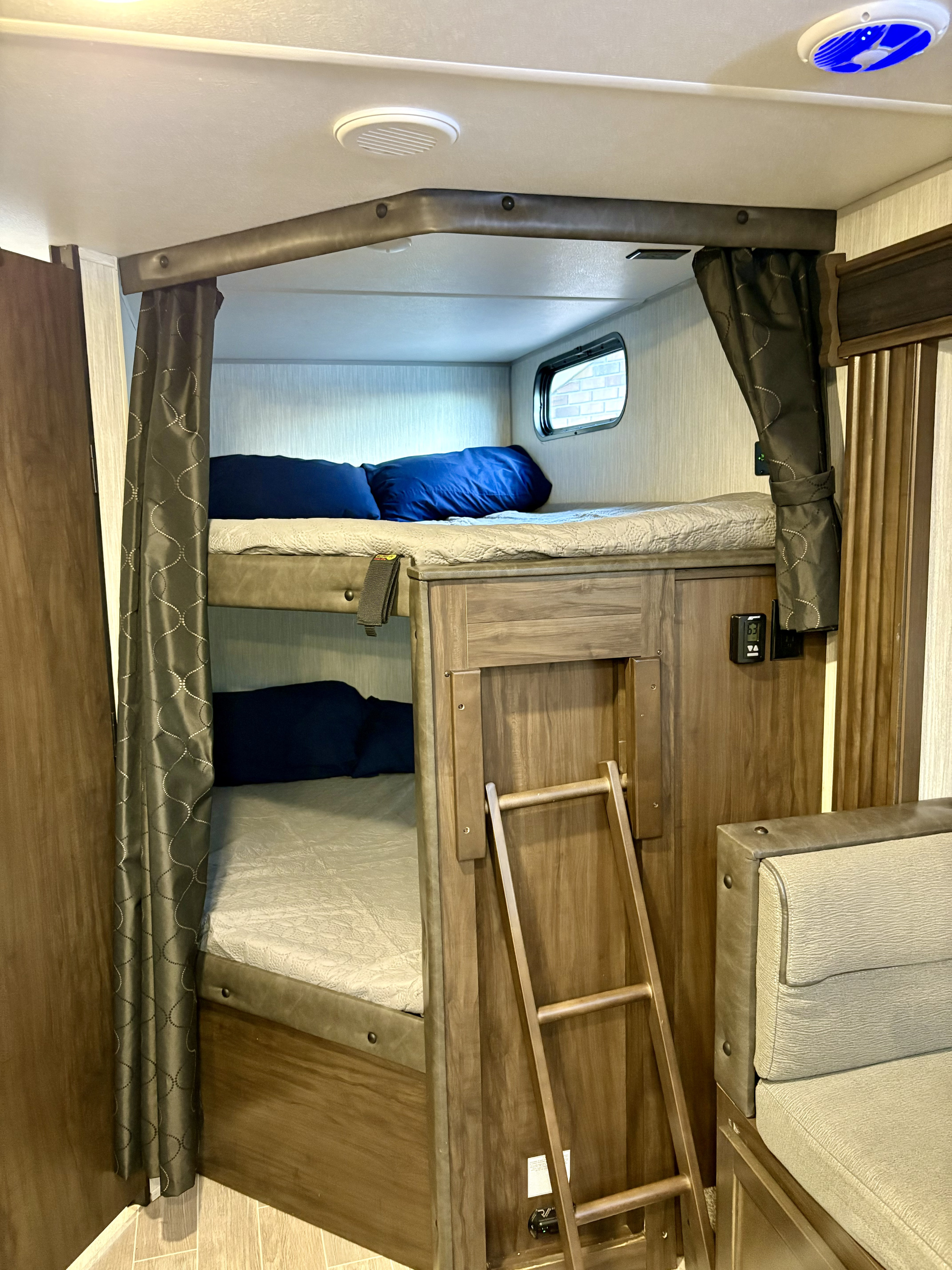 Inside an RV rental: two neatly made bunk beds with a ladder, window, and privacy curtains. Ideal for a family trip.. Forest River Cherokee Grey Wolf 2021