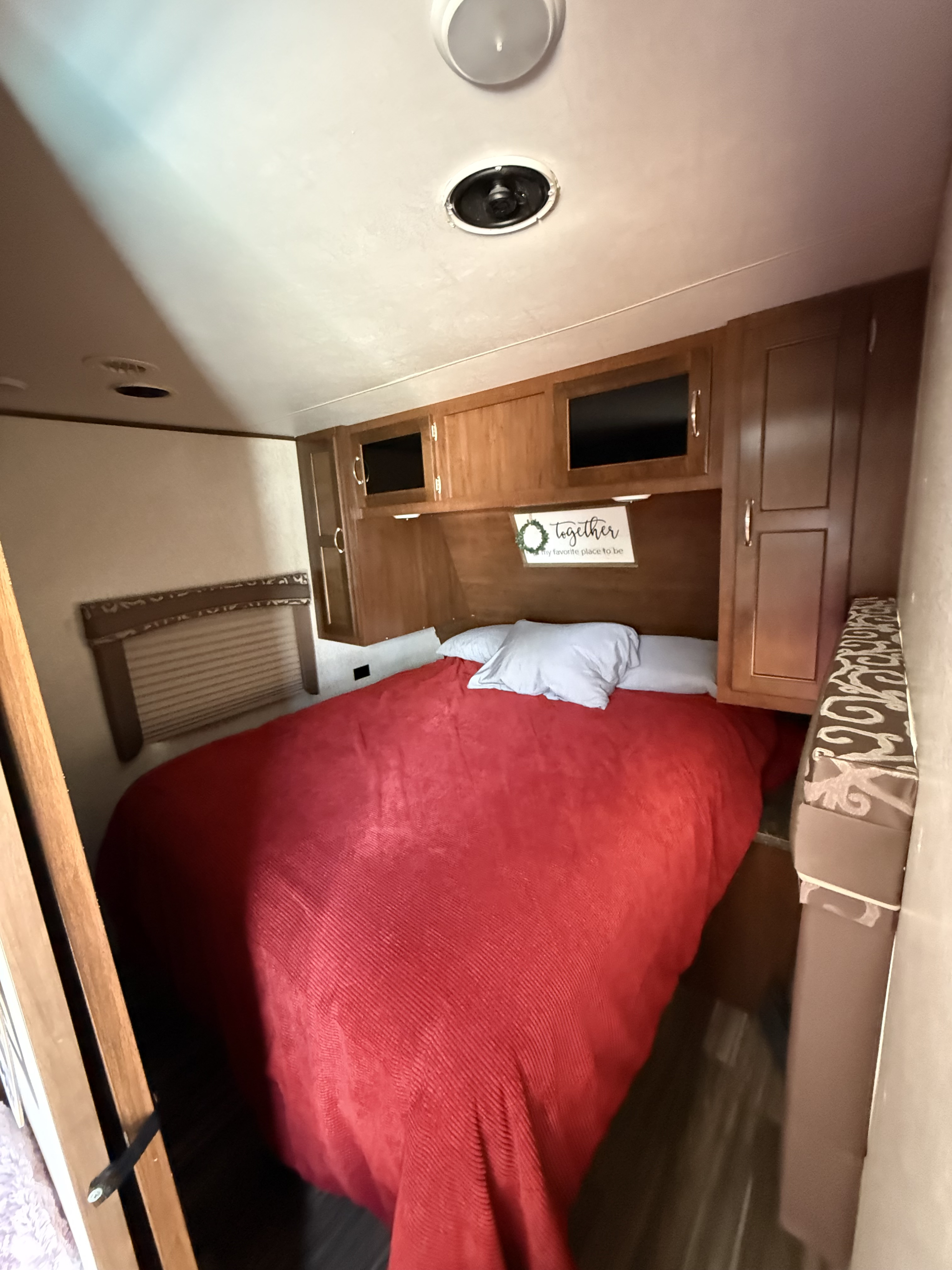 Cozy RV rental bedroom with a red bed, overhead cabinets, and TVs for a comfortable stay.. Jayco Jay Flight 2017