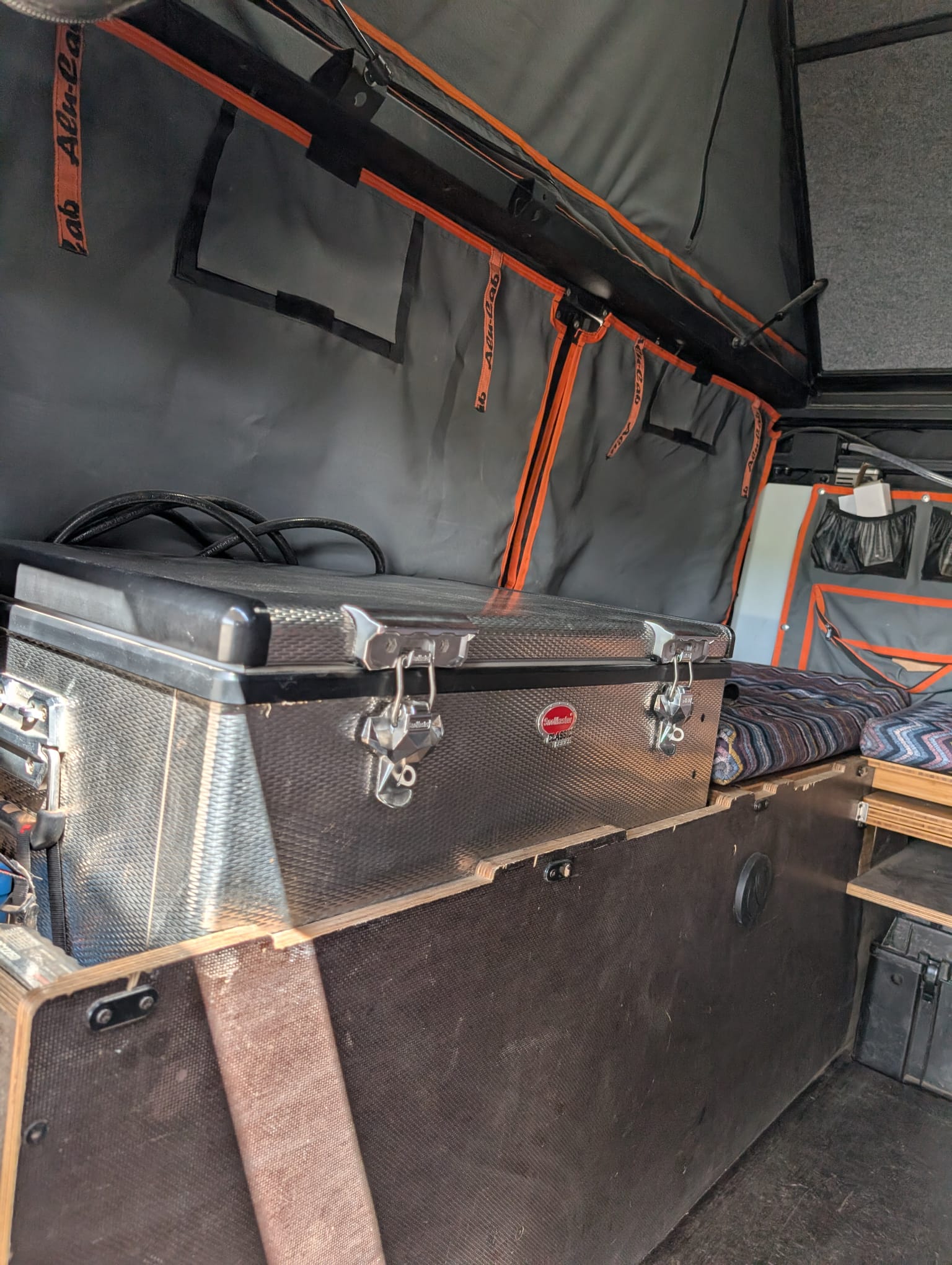 Inside this RV rental, an Alu-Cab pop-top tent and SnoMaster fridge are part of the organized camping setup with custom storage.. RAM Truck, ALucab camper 2500 2021