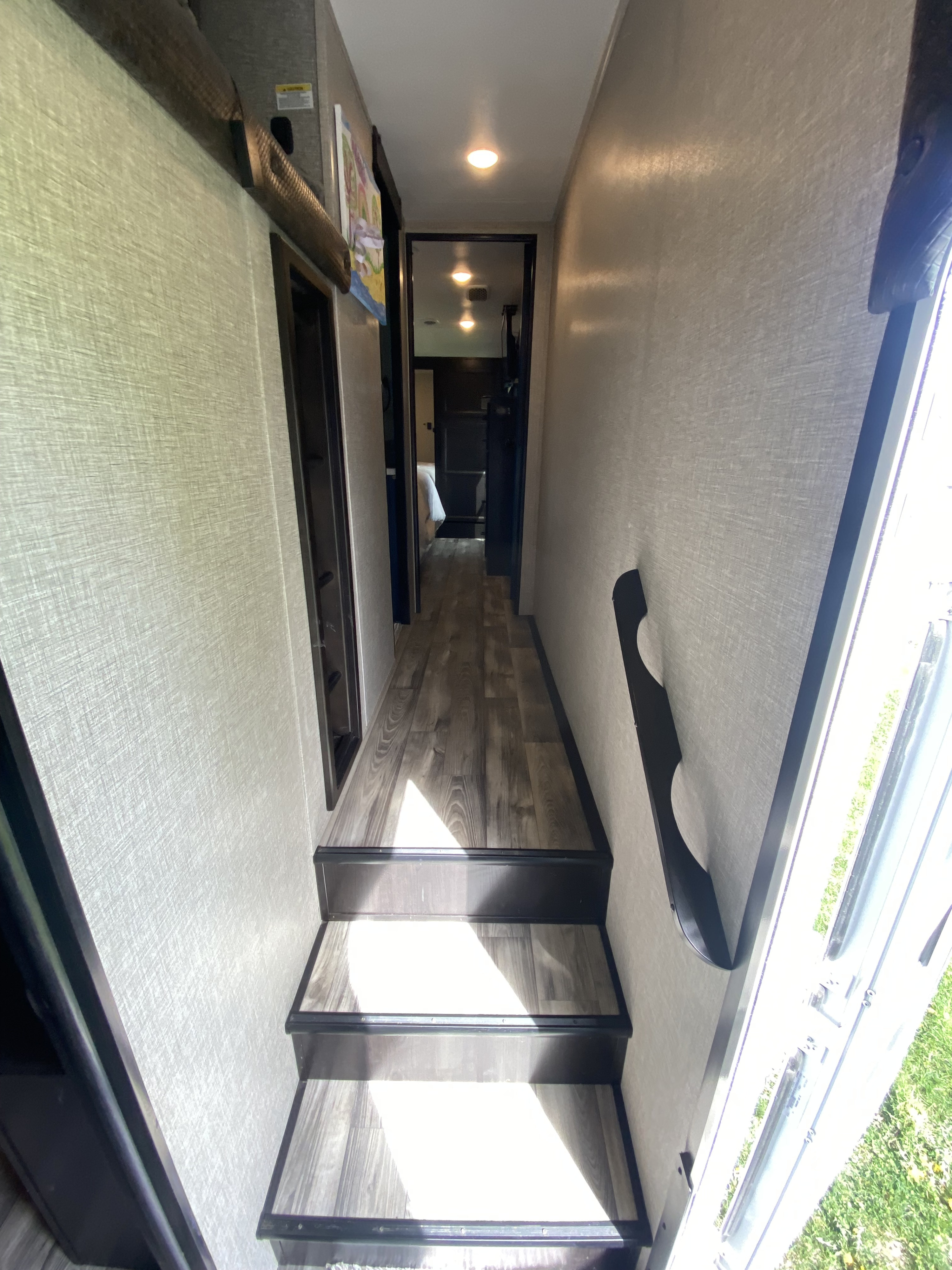 RV rental: Bright interior hallway with steps, leading to a cozy bedroom. Features wood-look flooring & compact living space.. Jayco Eagle 2022