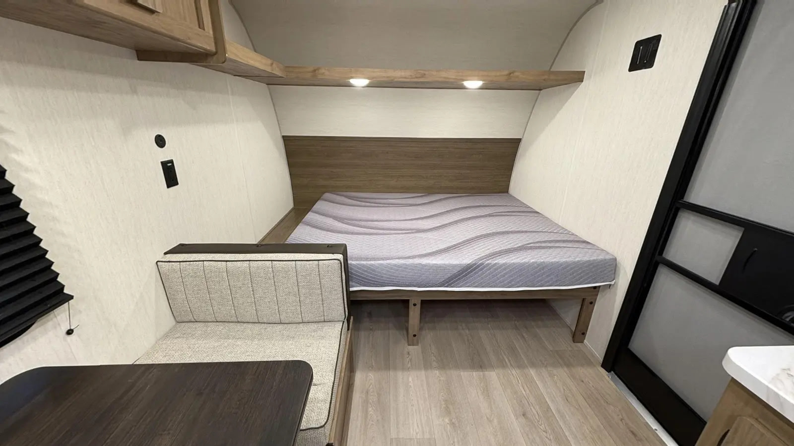 Inside this rv rental: a cozy bed with patterned mattress, dinette, and wood-toned cabinets. Compact and comfortable for travel.. Forest River Cherokee Wolf PUP 16LP 2025