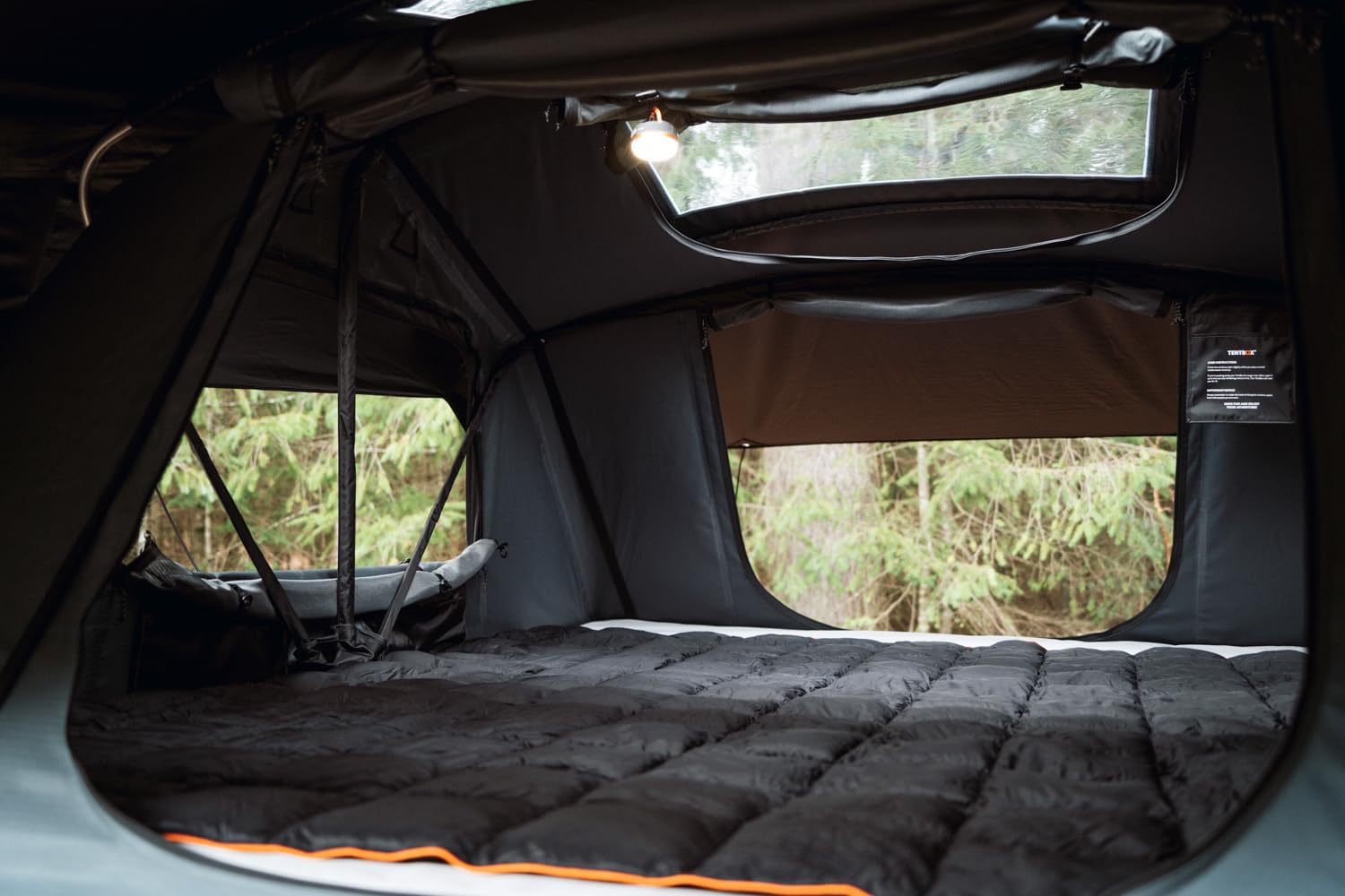Experience comfort in an RV rental! Inside this cozy rooftop tent: a plush bed, forest views, and built-in light for camping adventures.. USHI Chuck MAX 2025